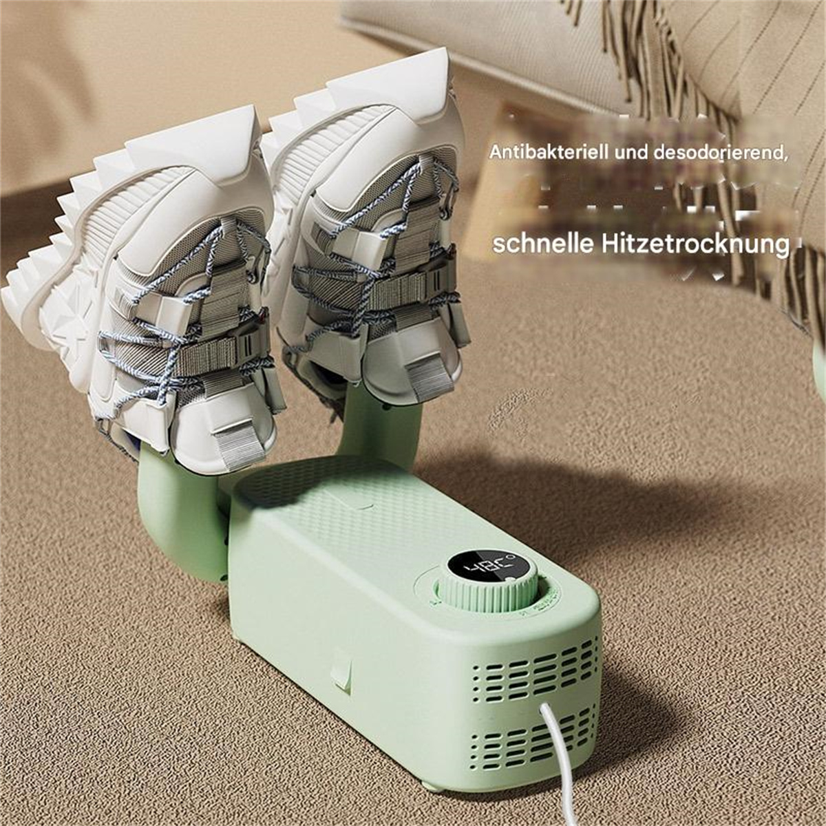 Weiße Turnschuhe trocknen auf einem grünen Schuhtrockner. Der Trockner hat ein digitales Display mit der Temperatur. Der Hintergrund ist beige.