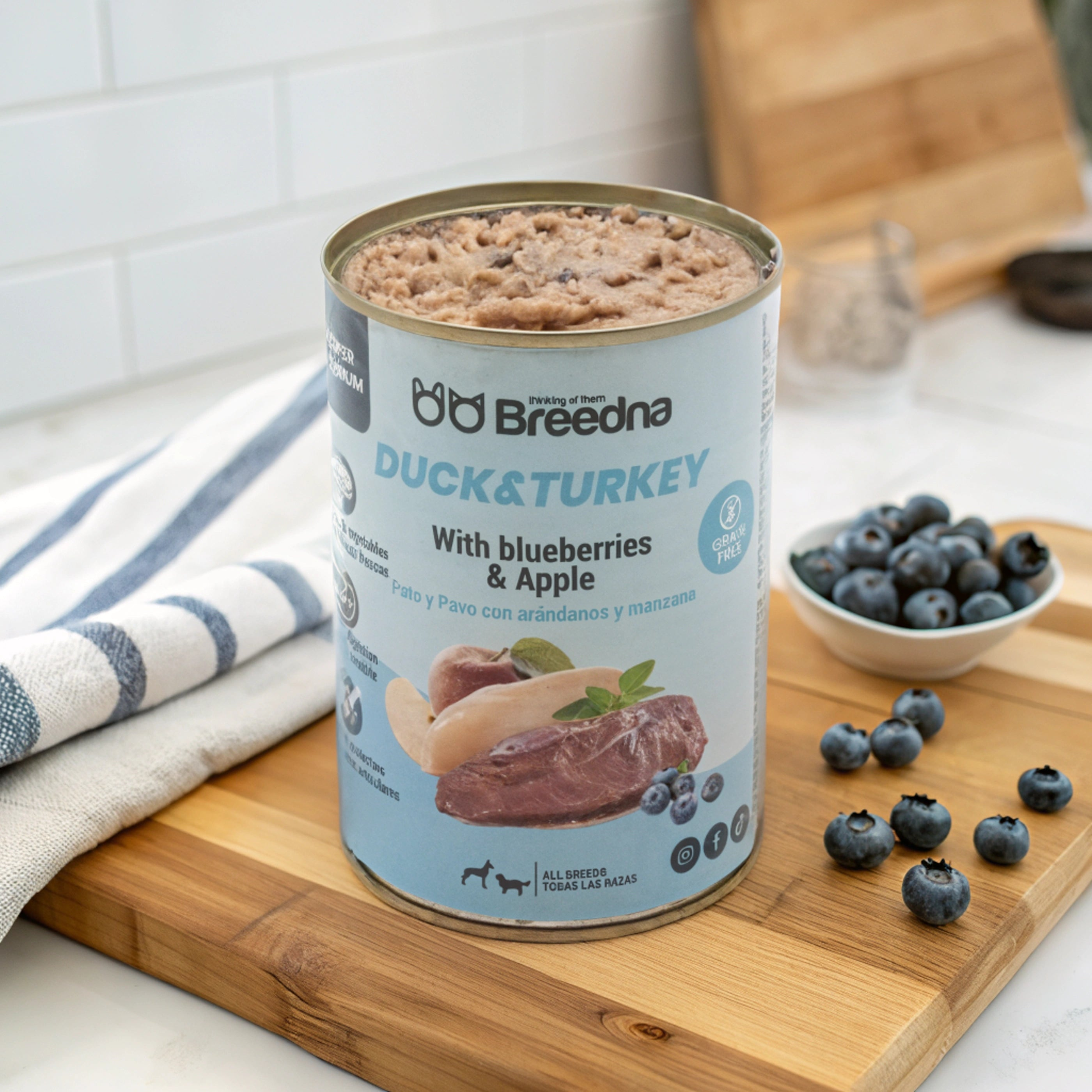 Una lata de comida para perros Breedna de pato y pavo con arándanos y una manzana en una tabla de cortar de madera.