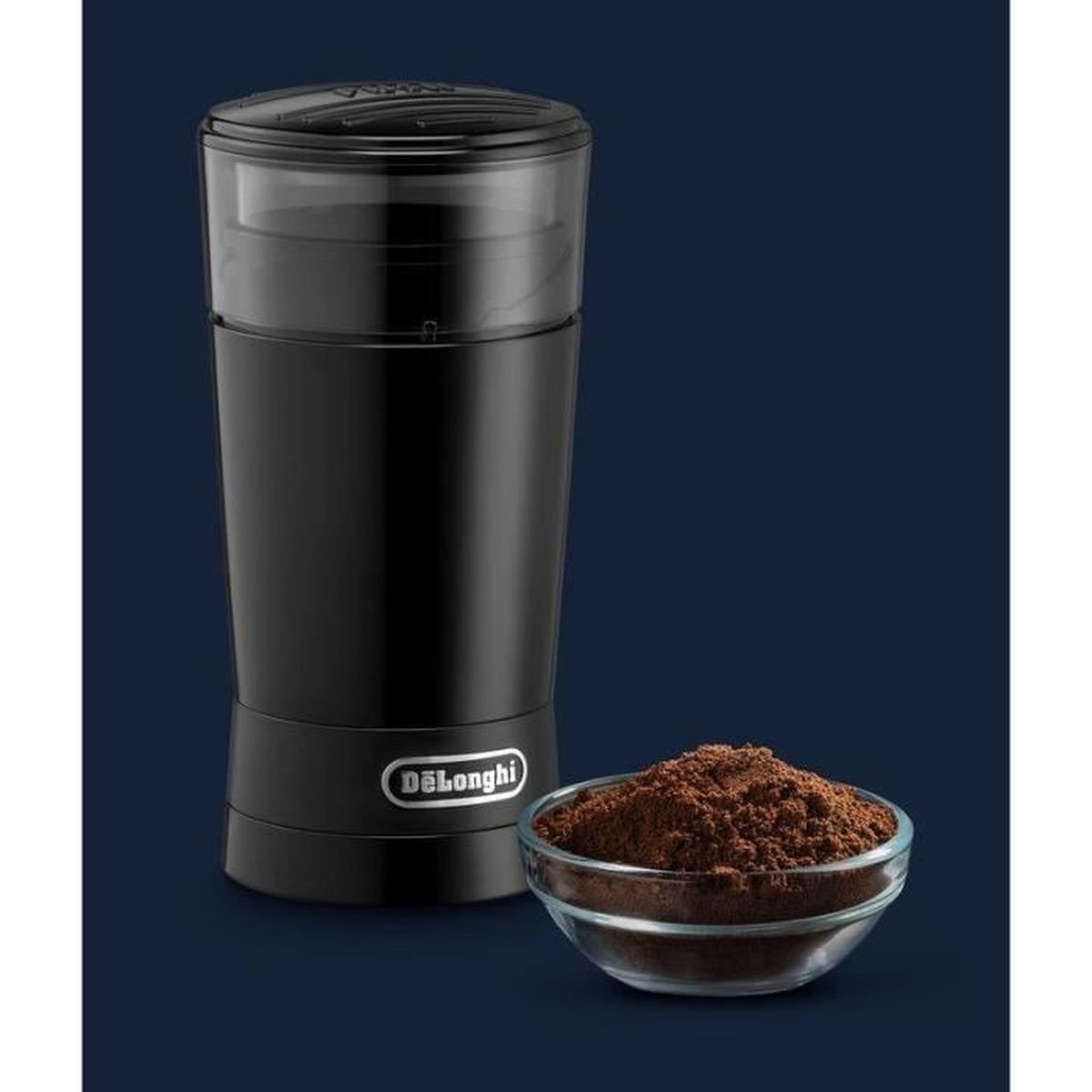 Un molinillo de café DeLonghi negro con café molido en un cuenco de vidrio. Fondo azul oscuro.