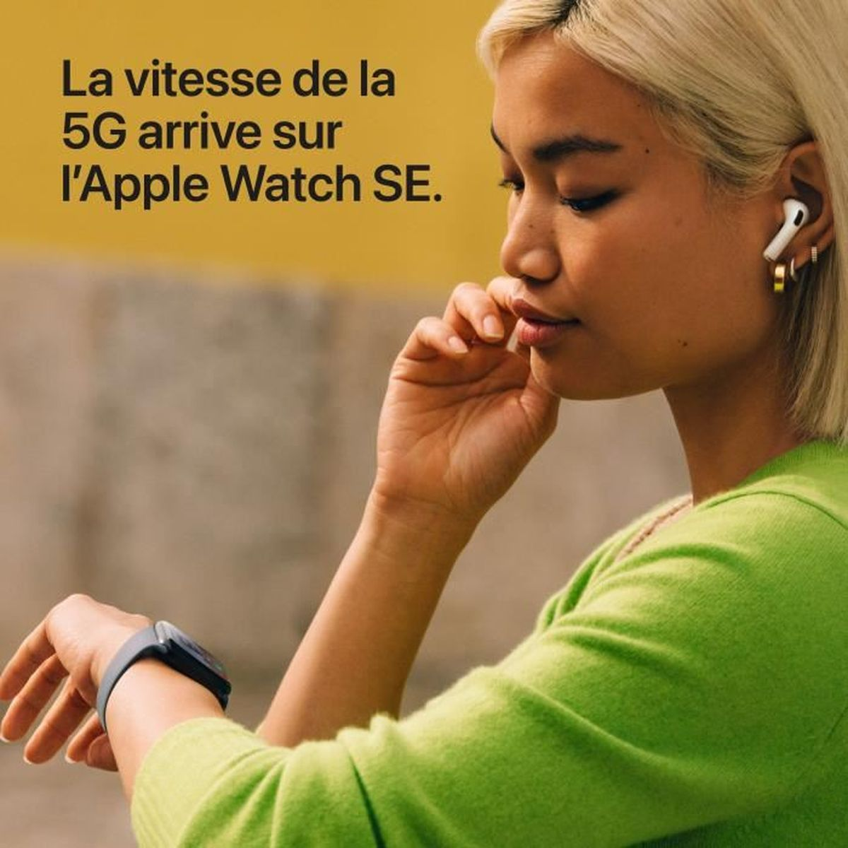 Kobieta w zielonym swetrze patrzy na zegarek. Widoczne są również słuchawki i pierścionek. Tekst: 5G trafia do Apple Watch SE.