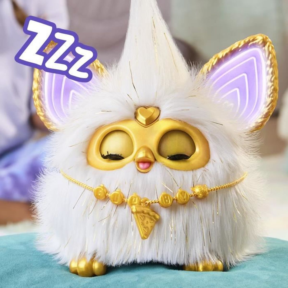 Ein weißes Furby mit geschlossenen Augen, goldenen Akzenten und einer Halskette. Ein ZZZ-Zeichen deutet auf Schlaf hin.