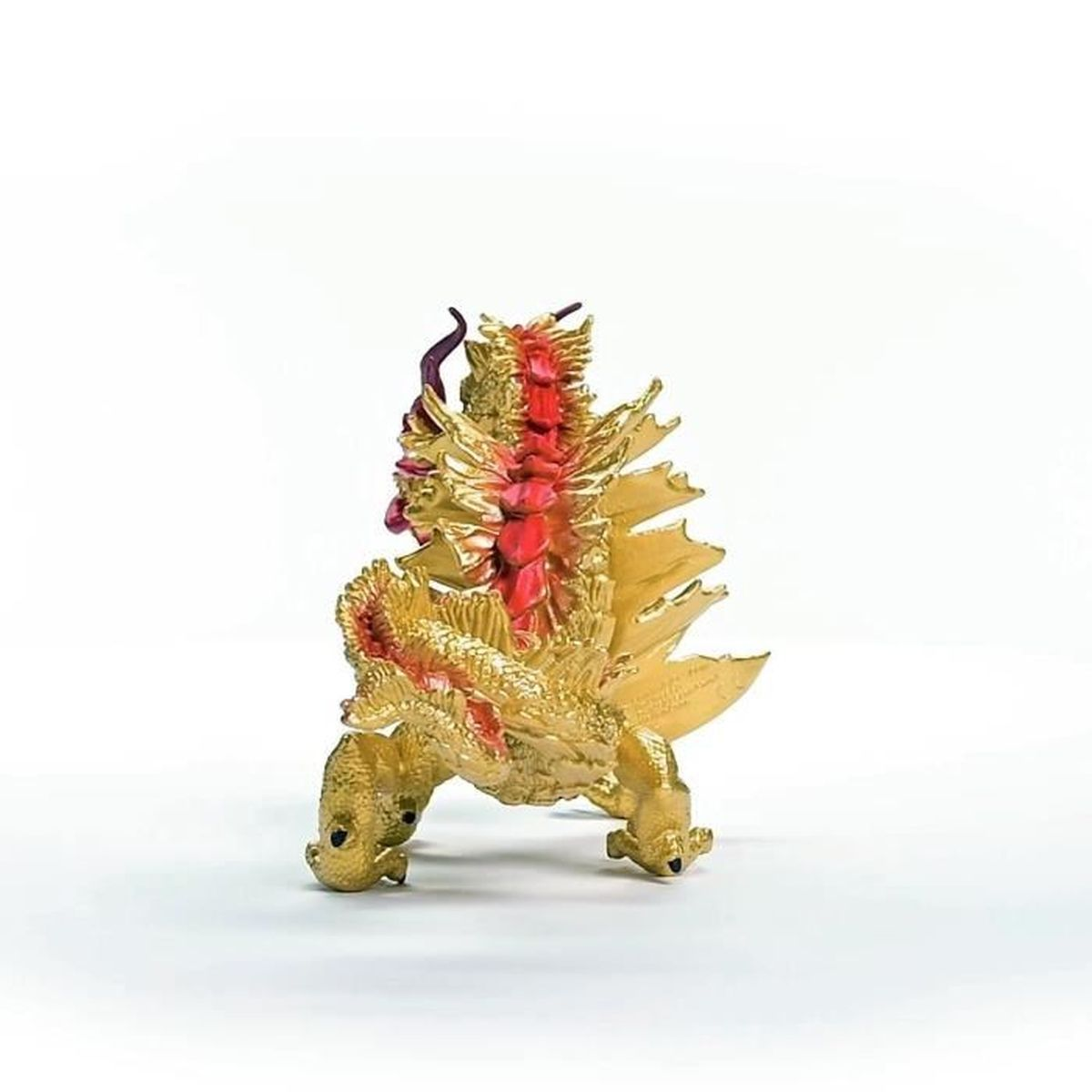 Una statuetta di drago dorato con accenti rossi sulla schiena, sulle ali e sul viso. Su sfondo bianco.