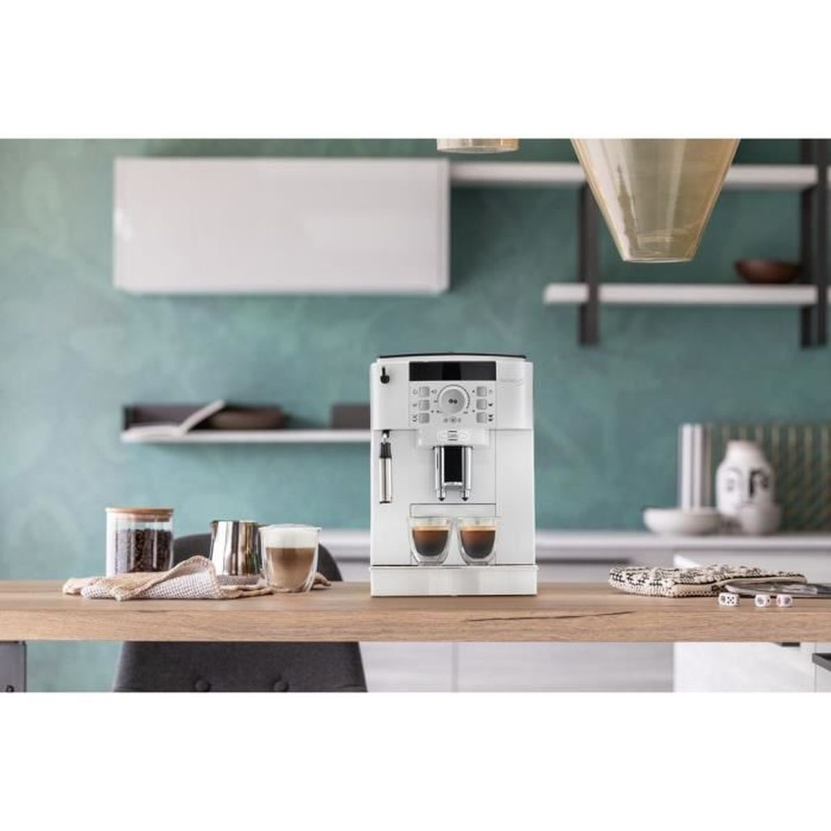 Una macchina per espresso bianca è appoggiata su un tavolo di legno con due colpi di espresso. Altri oggetti includono chicchi di caffè, uno schiumatore di latte e un bicchiere.