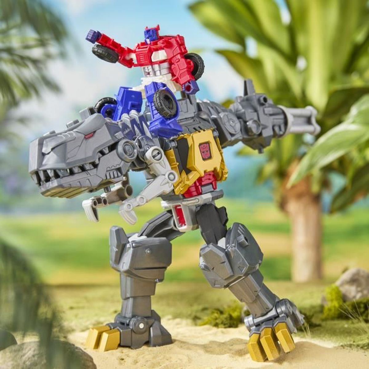 Un giocattolo Transformer, un camion rosso su un dinosauro grigio, ambientato in un ambiente tropicale con vegetazione verde e sabbia.