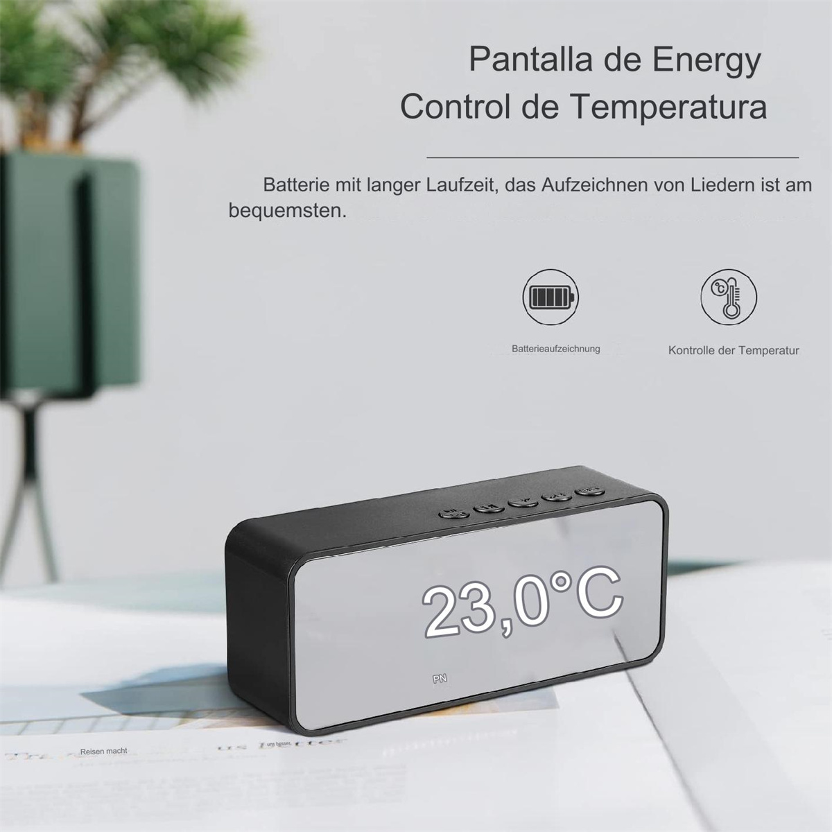 Eine schwarze Digitaluhr zeigt 23,0°C an. Sie hat Knöpfe oben und steht auf einer weißen Oberfläche. Text auf Spanisch und Deutsch ist oben.