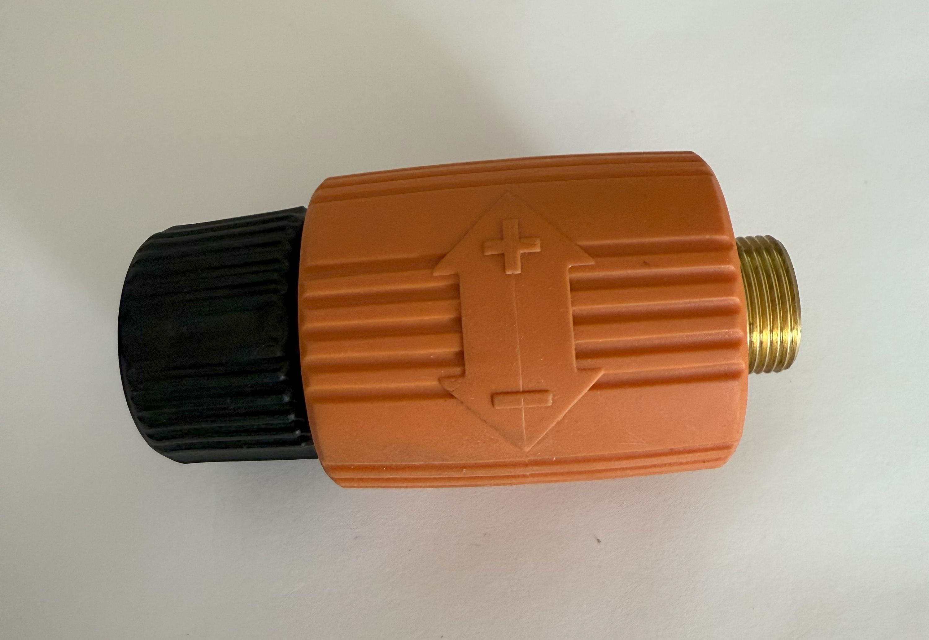 Ein orangefarbener und schwarzer Stecker. Der orangefarbene Teil hat ein Pfeilsymbol. Das Ende des Steckers ist goldfarben.