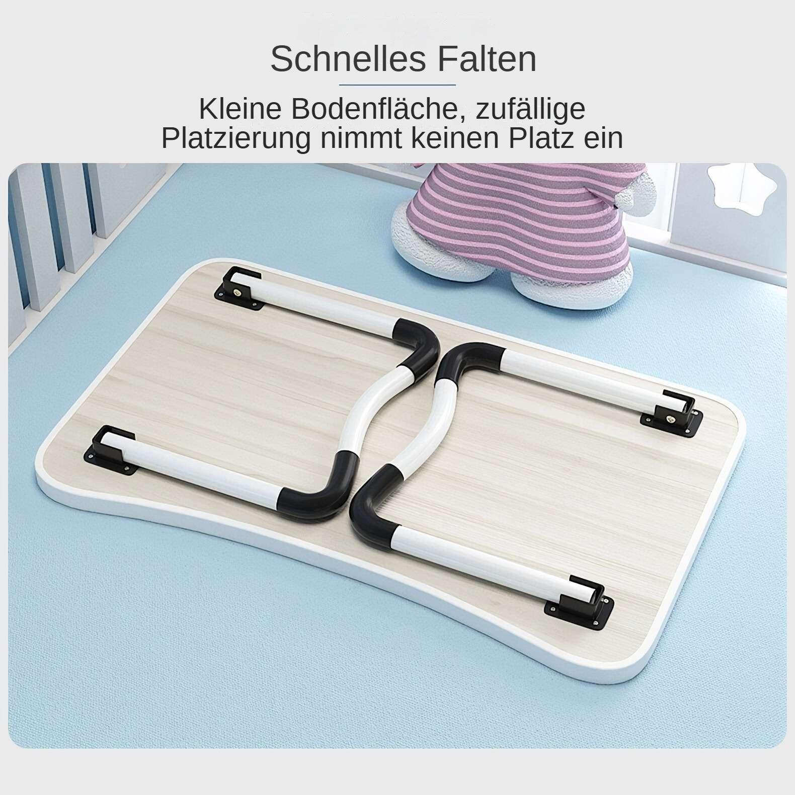 Ein zusammenklappbarer Laptop-Tisch aus Holz mit weißen Beinen und schwarzen Gelenken, auf blauer Oberfläche. Oben ist ein Spielzeug.