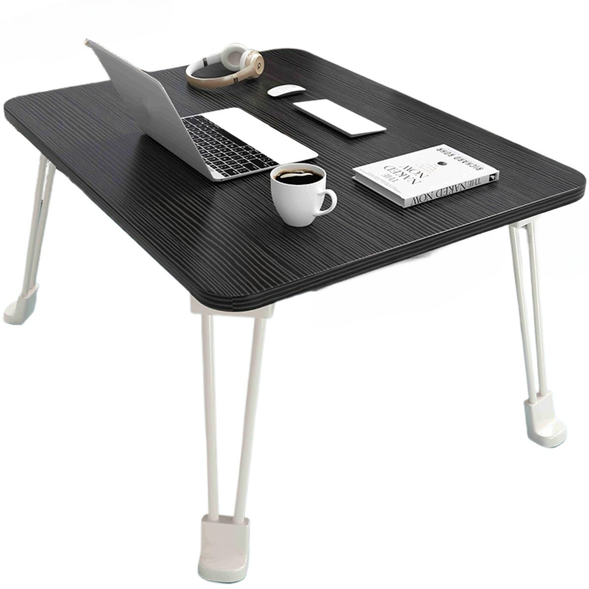 Ein schwarzer Laptop-Tisch mit Laptop, Kopfhörern, Maus, Telefon, Kaffeetasse und Buch. Weiße Beine stützen den Tisch.