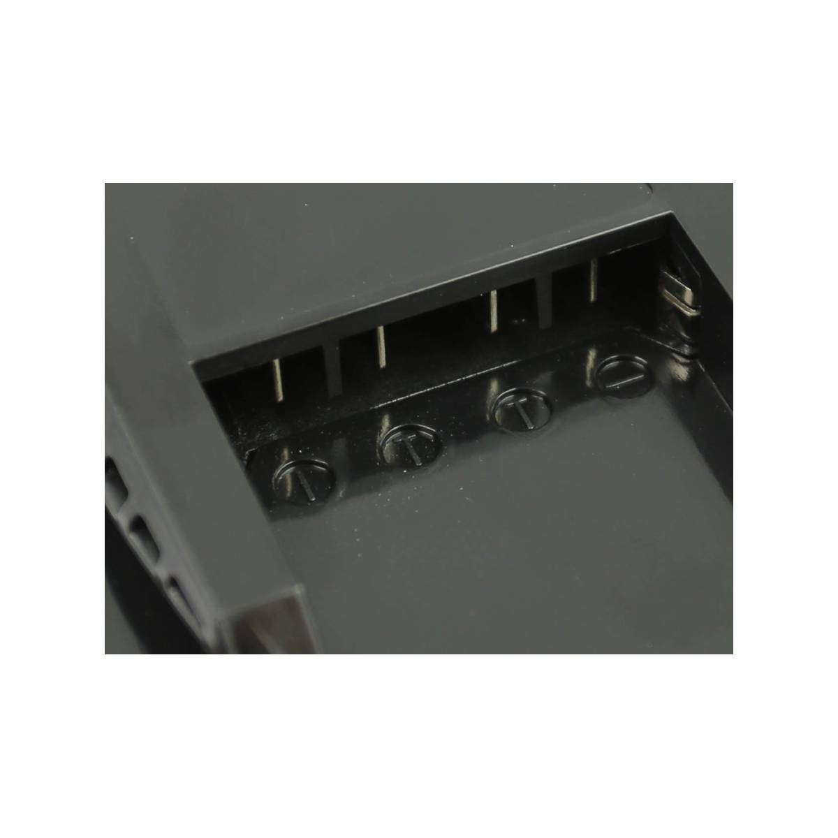 Primo piano di un componente elettrico grigio scuro con morsetti a vite e pin metallici verticali. Lo sfondo è bianco.