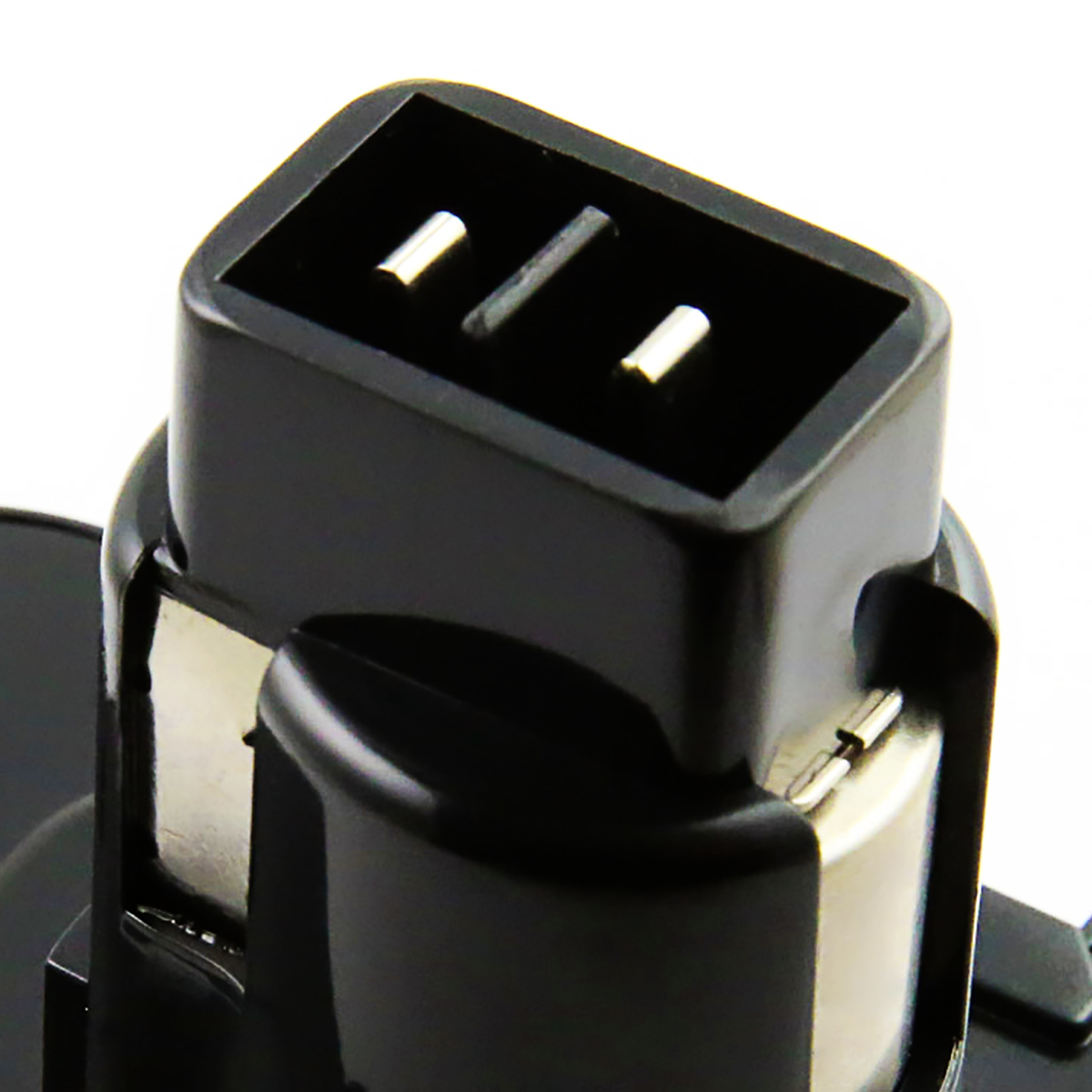 Primo piano di un connettore elettrico nero con due pin metallici e una fessura. Lo sfondo è bianco.