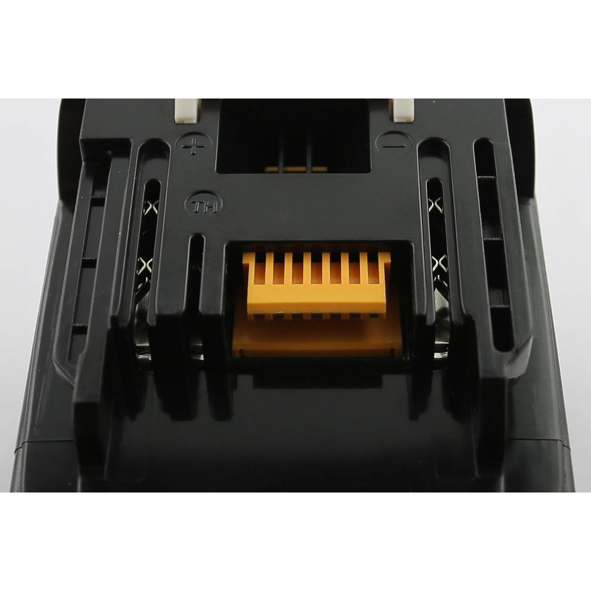 Primo piano di una base batteria nera con connettori elettrici gialli. La parte superiore ha simboli più e meno con una 'X'.
