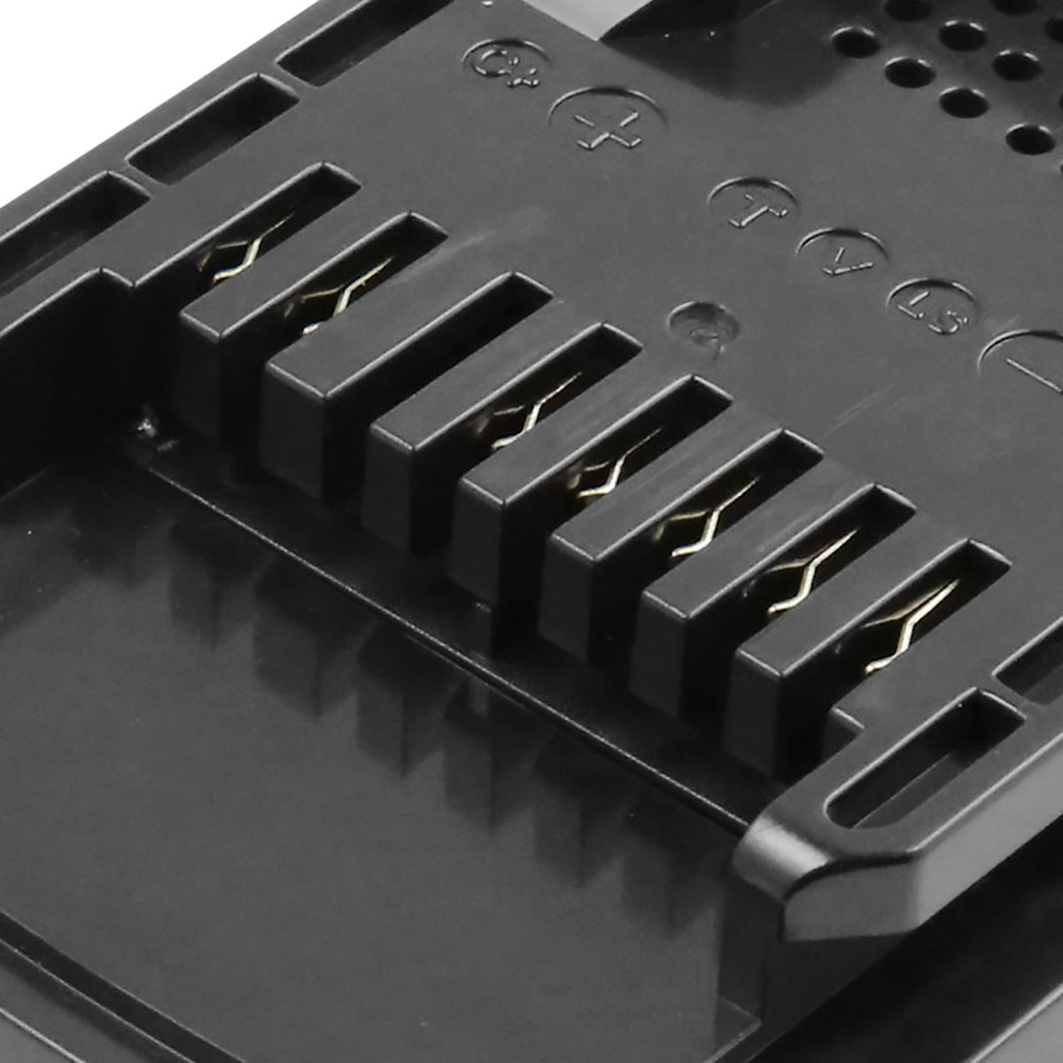 Primo piano di un dispositivo in plastica nera con più fessure e contatti metallici color oro. Simboli visibili sulla superficie.