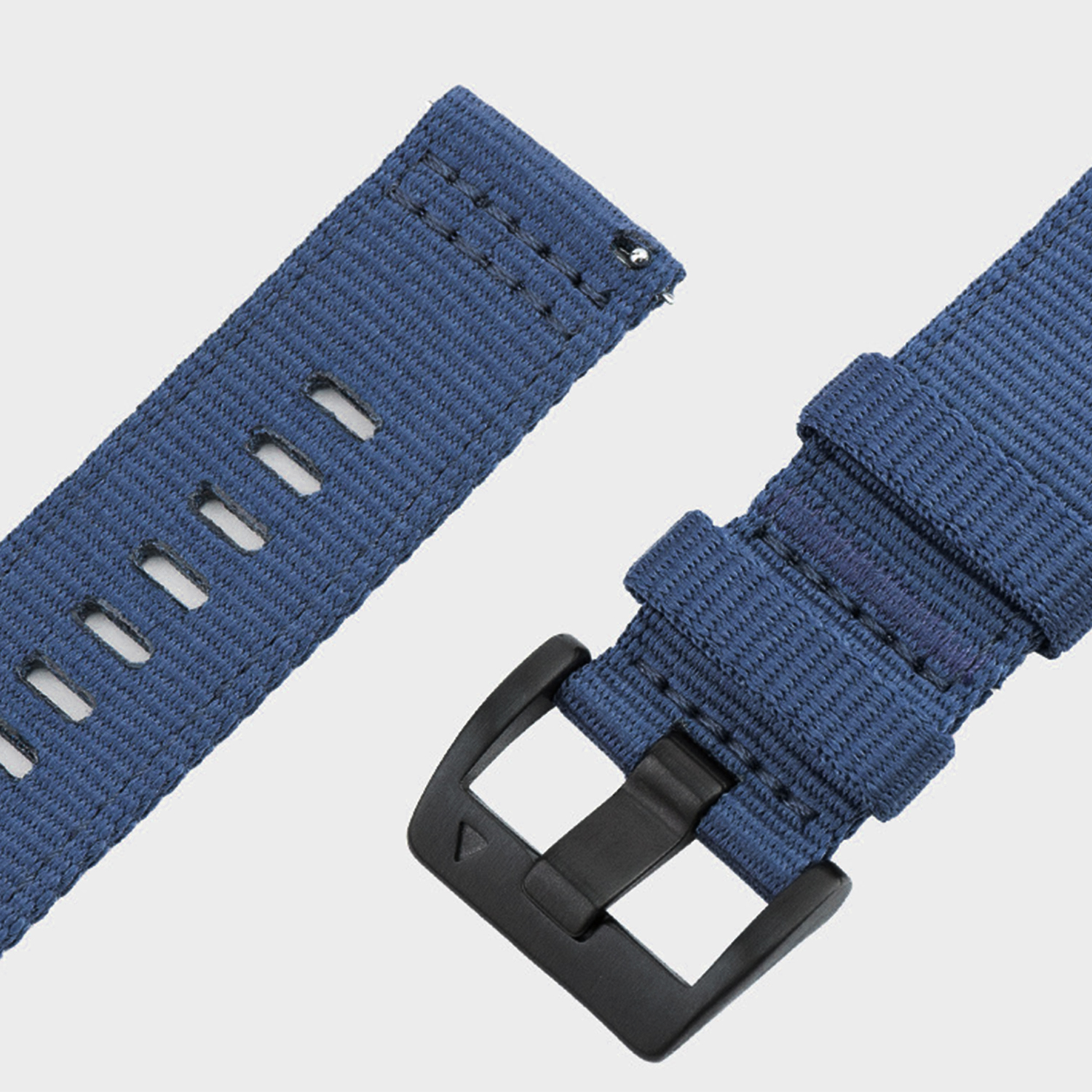 Primo piano di cinturini per orologi in nylon blu. Un cinturino ha dei fori, l'altro ha una fibbia nera. Entrambi su sfondo grigio chiaro.