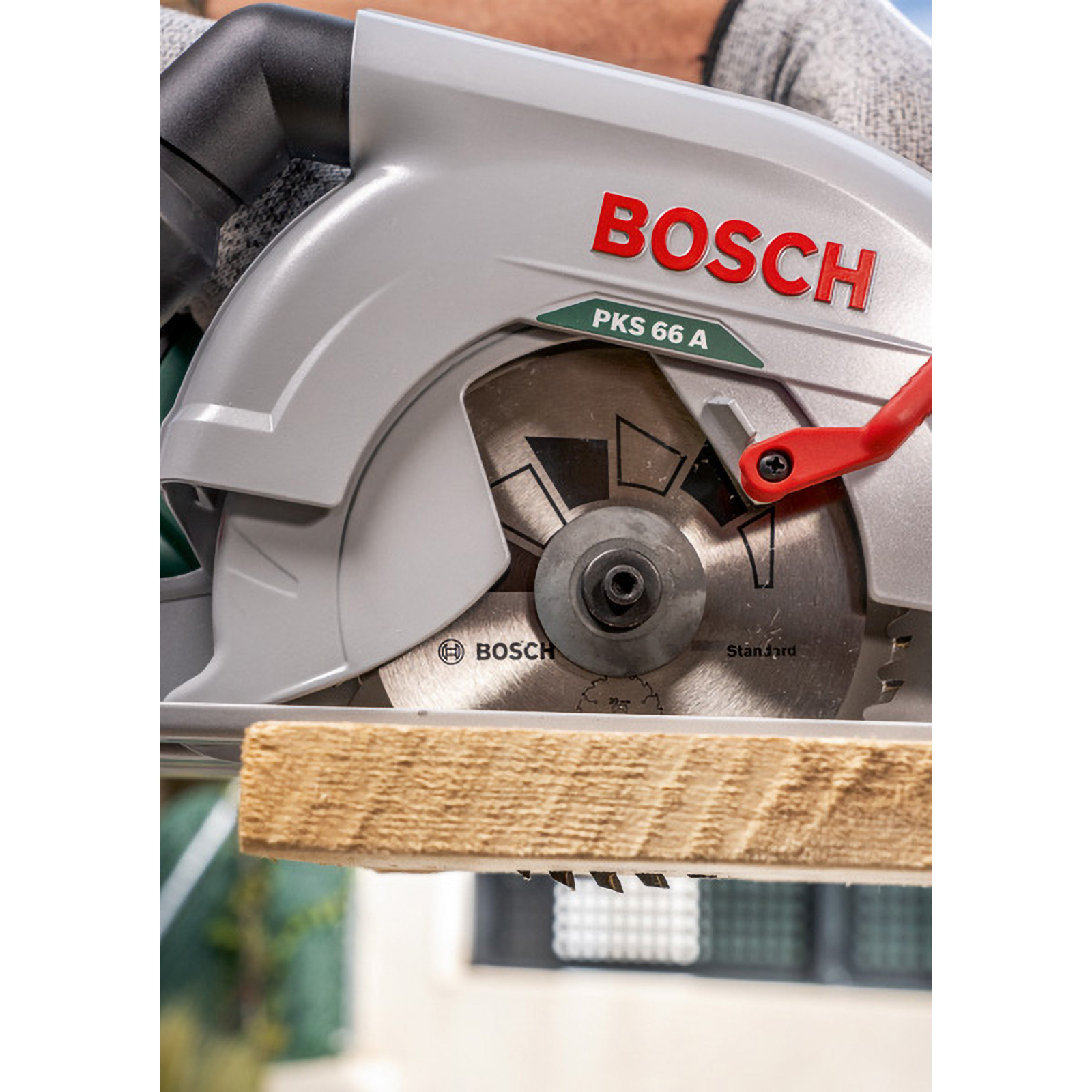 Eine Bosch-Kreissäge schneidet Holz. Die Säge ist silber und rot. Das Holz ist hellbraun und wird geschnitten.