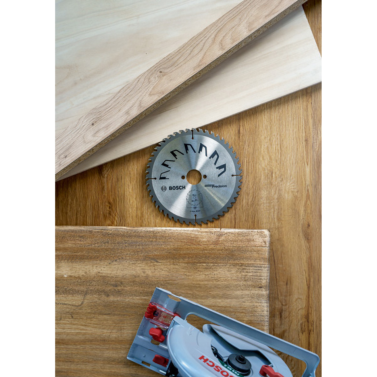 Eine Kreissägeblatt, Holzstücke und eine elektrische Säge liegen auf einer Holzoberfläche.