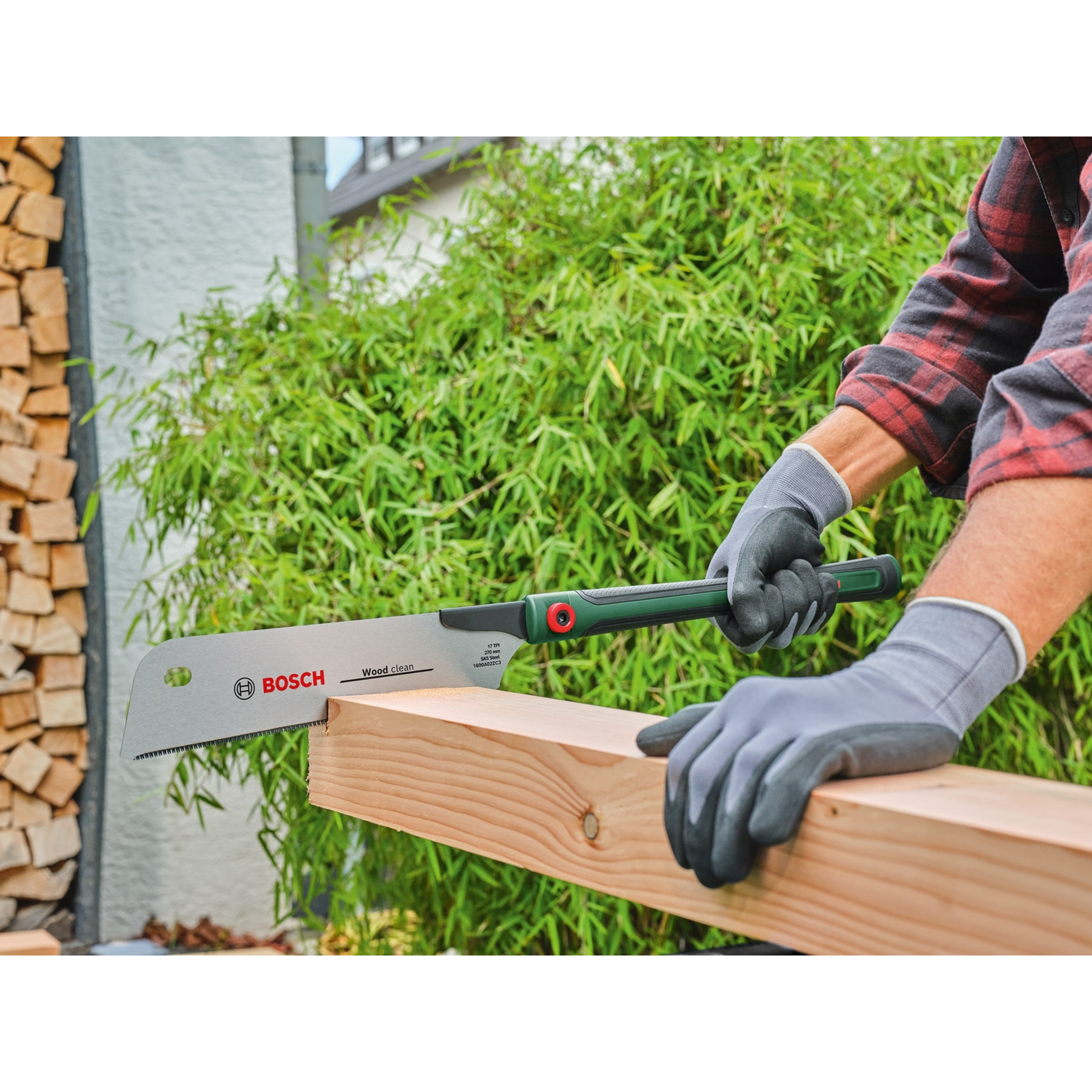Una persona segna una tavola di legno con un seghetto Bosch. La scena ha uno sfondo verde e una pila di legno a sinistra.