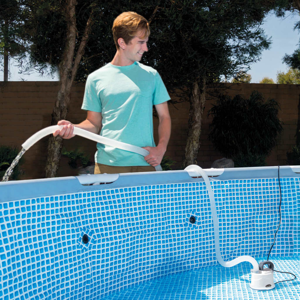 Ein Mann füllt einen Pool mit einem Schlauch. Der blaue Pool hat ein weißes Gittermuster. Bäume und eine Backsteinmauer sind im Hintergrund.