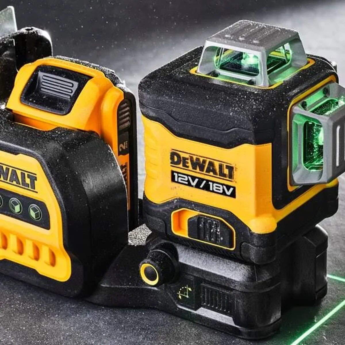 Zwei schwarz-gelbe DeWalt-Laserwasserwaagen, eine emittiert einen grünen Laser. Die Geräte stehen auf einer grauen Oberfläche, mit grüner Laserlinie.