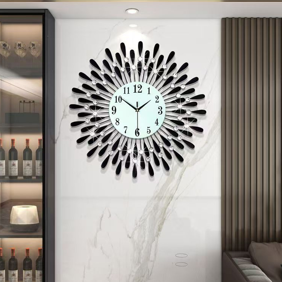 Eine dekorative Wanduhr mit hellblauem Zifferblatt und schwarzen, tropfenförmigen Akzenten. Sie ist an einer Marmorwand befestigt. Links ist ein Weinschrank.