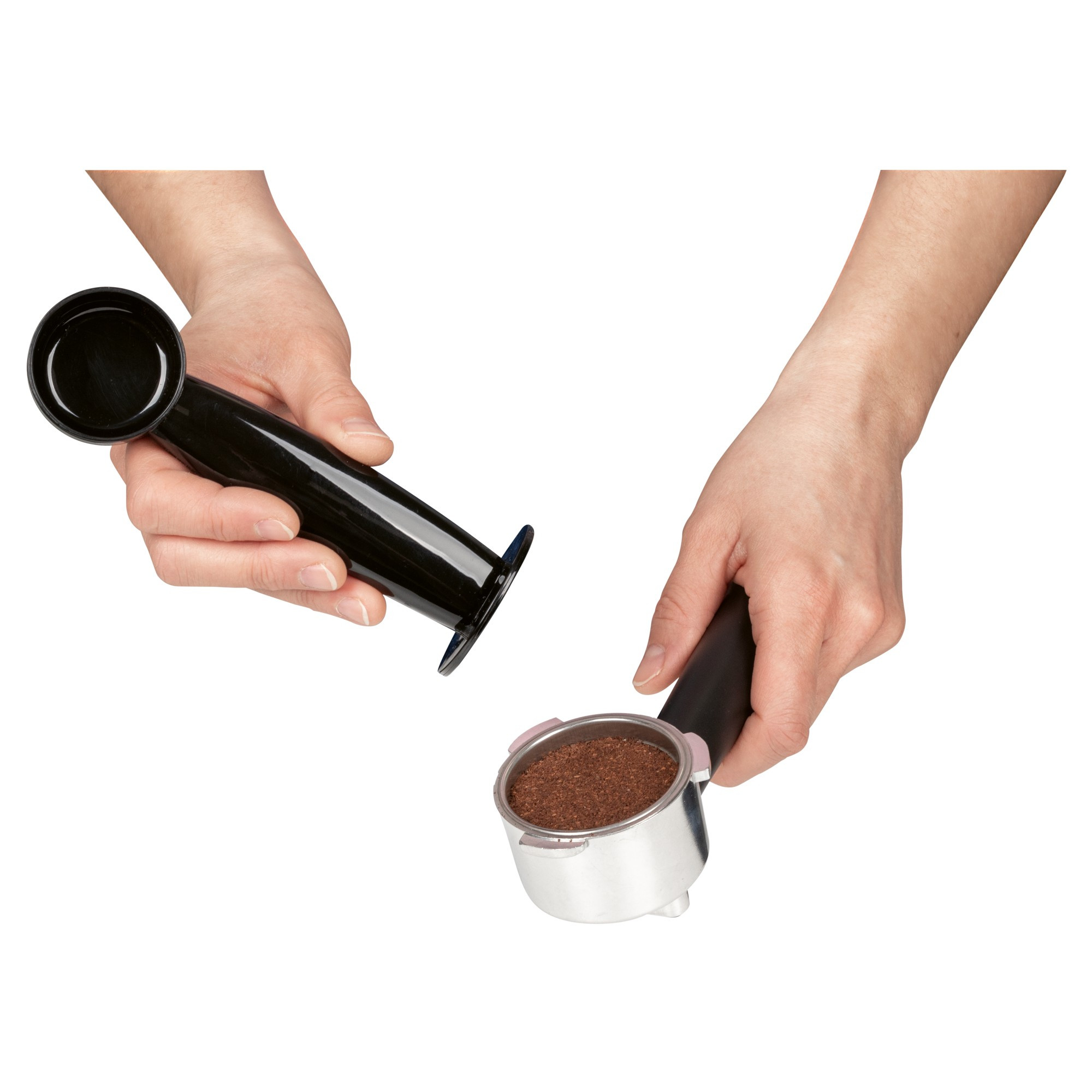 Dłonie trzymają czarny ubijak i kolbę wypełnioną zmieloną kawą, gotową do ubijania. Białe tło.