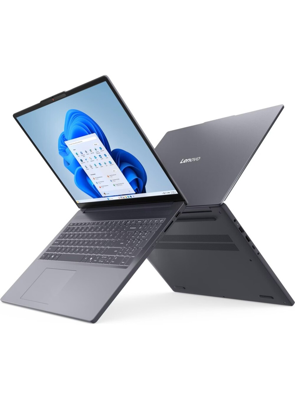 Açık gri bir Lenovo dizüstü bilgisayar. Ekran Windows 11 arayüzünü gösteriyor. Arkasında kapalı başka bir dizüstü bilgisayar var.