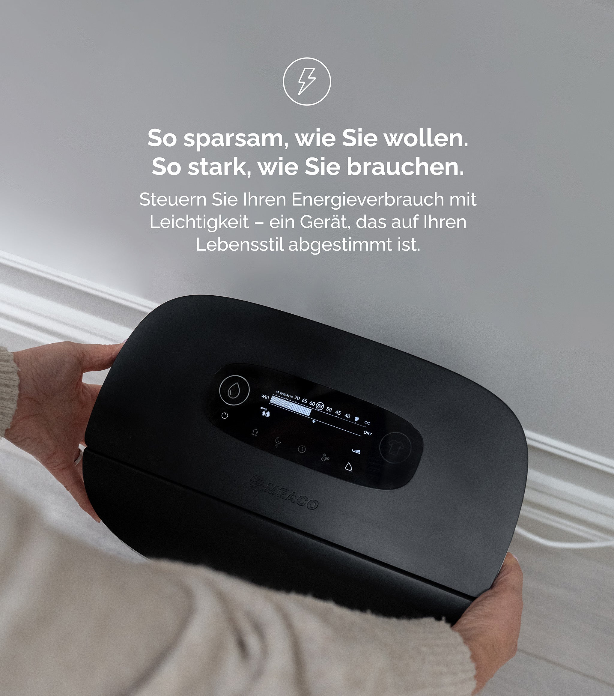 Osoba trzyma czarny osuszacz powietrza. Tekst w języku niemieckim wspomina zużycie energii i styl życia.