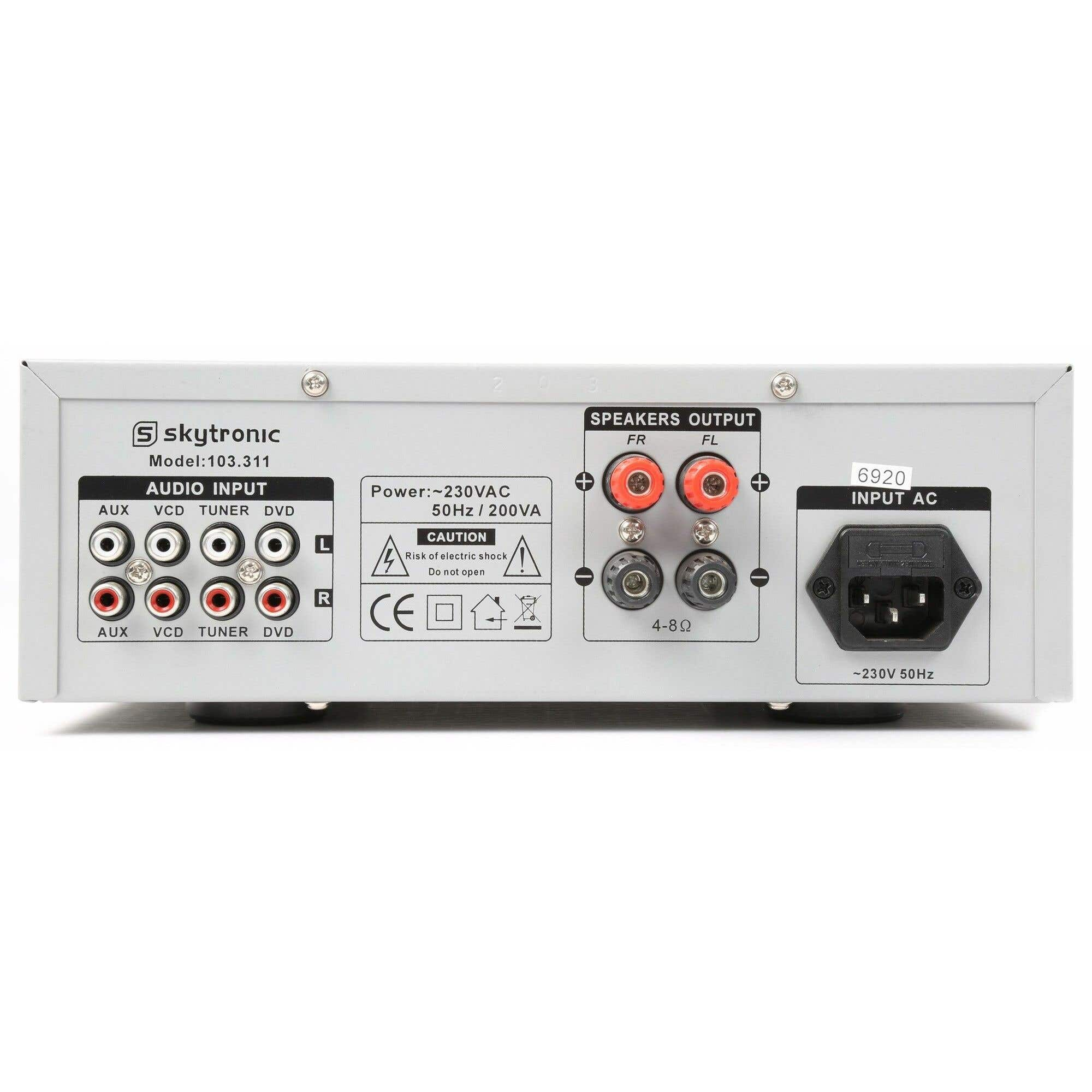 Panel trasero de un amplificador Skytronic con entradas de audio, salidas de altavoz, entrada de alimentación y etiquetas de advertencia.