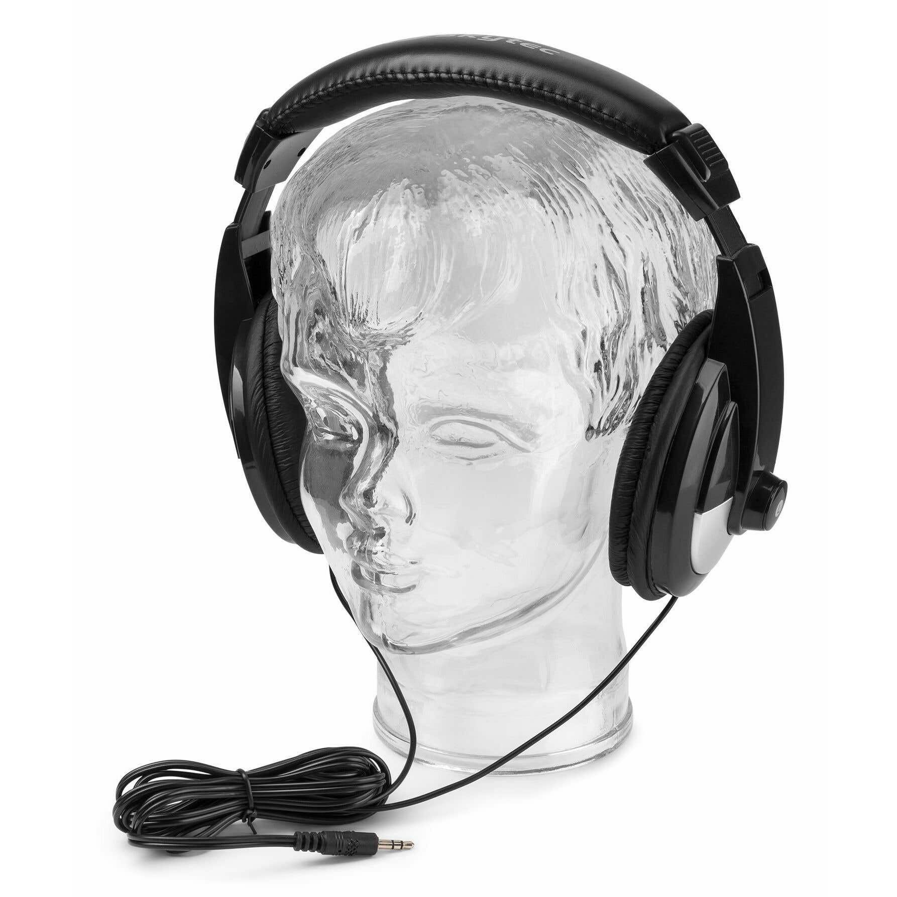 Auriculares negros sobre una cabeza de maniquí transparente. Un cable y enchufe negros en primer plano. Fondo blanco.