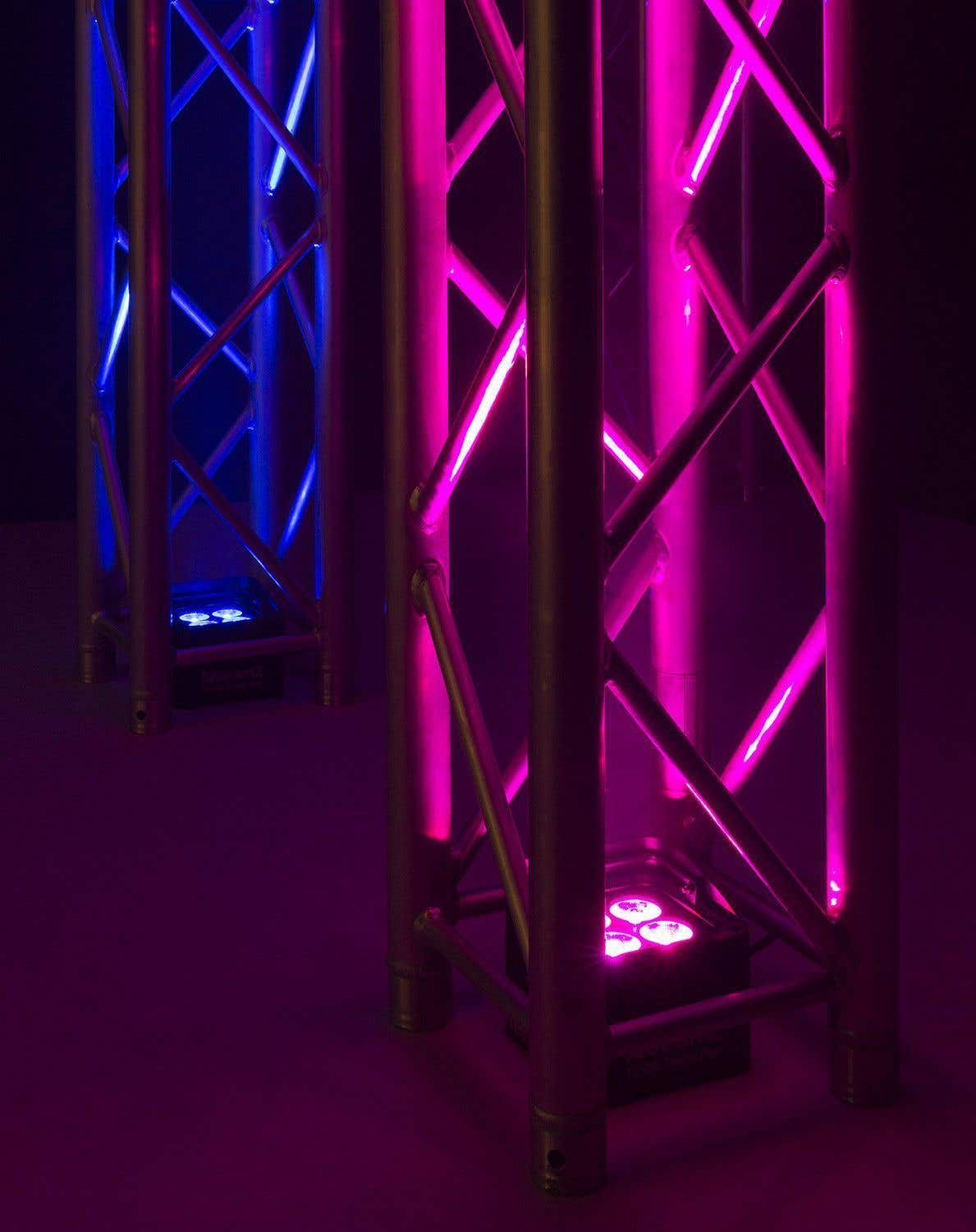 Estructuras de entramado metálico iluminadas con luces azules y rosas. La escena es oscura, con las luces creando un brillo vibrante.