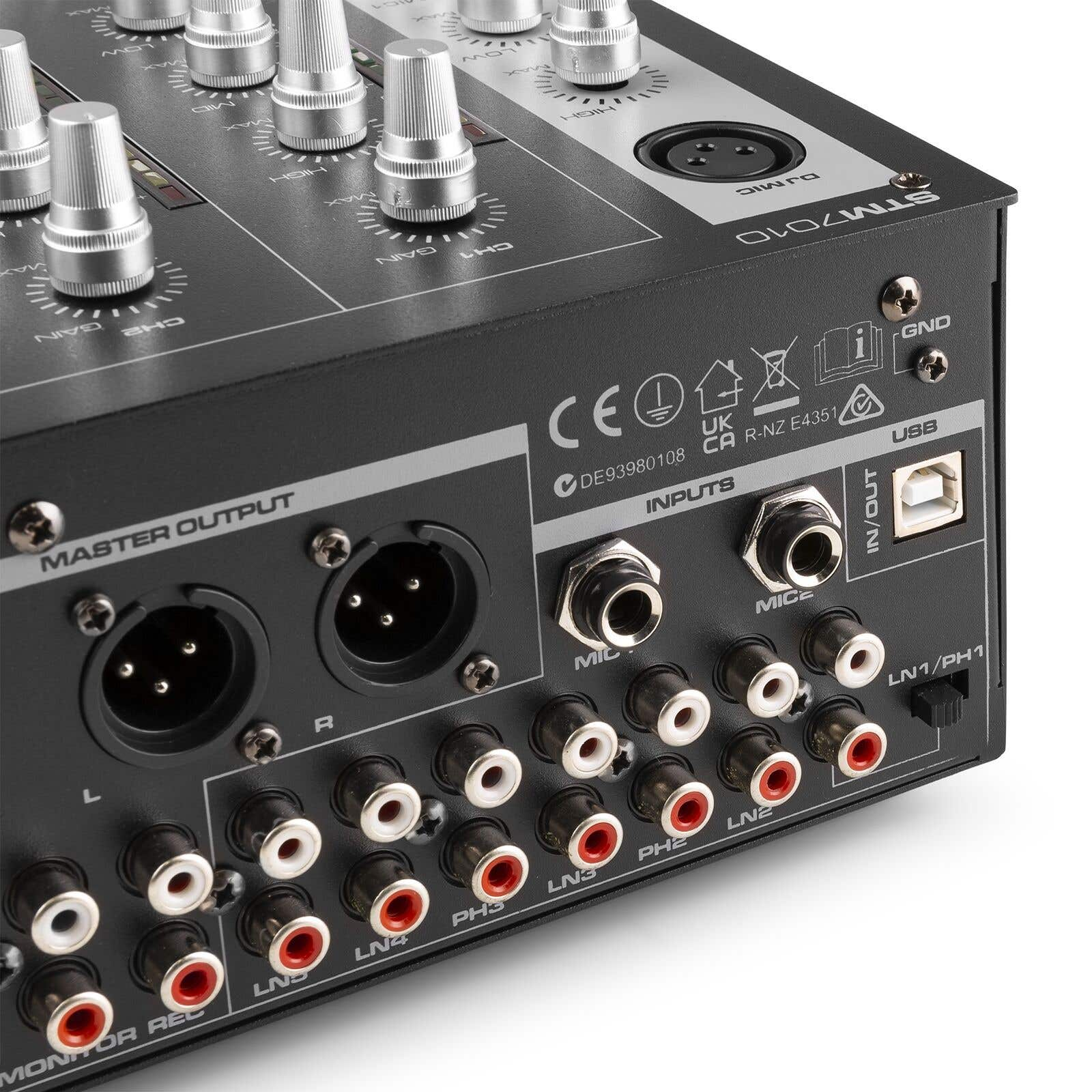 Primer plano de un mezclador de audio negro con perillas plateadas y varias entradas/salidas, incluyendo USB.