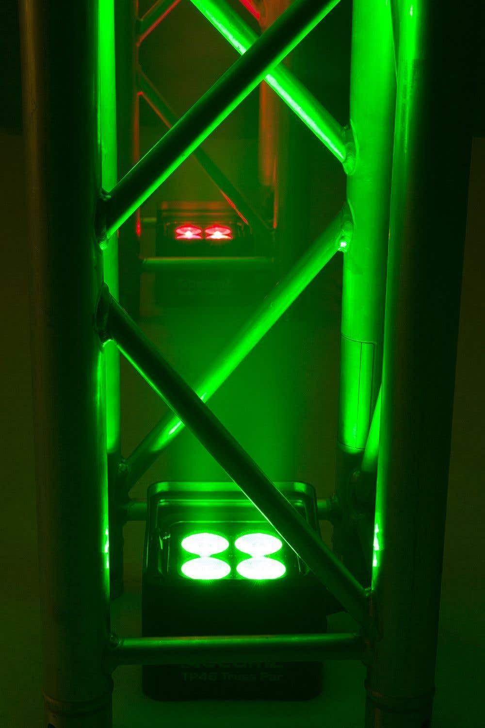 Luces de escenario verdes y rojas sobre una estructura metálica. Brillantes haces verdes y focos rojos en la estructura.