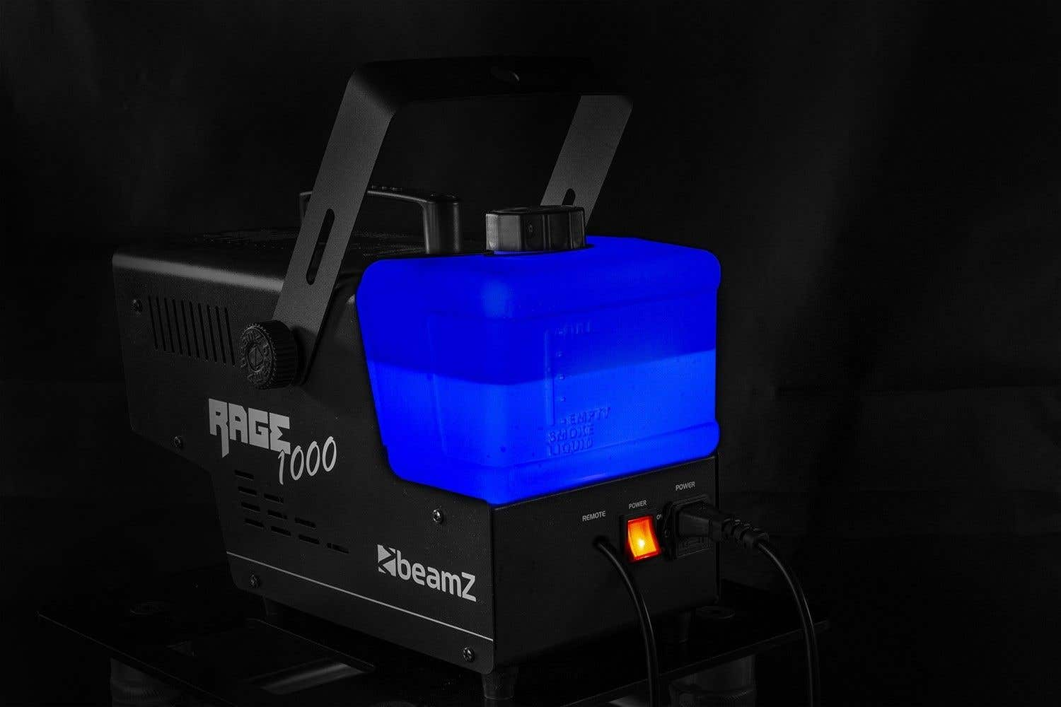 Una máquina de humo negra Beamz Rage 1000 tiene un tanque de líquido azul y un botón de encendido iluminado. Está sobre una superficie negra.