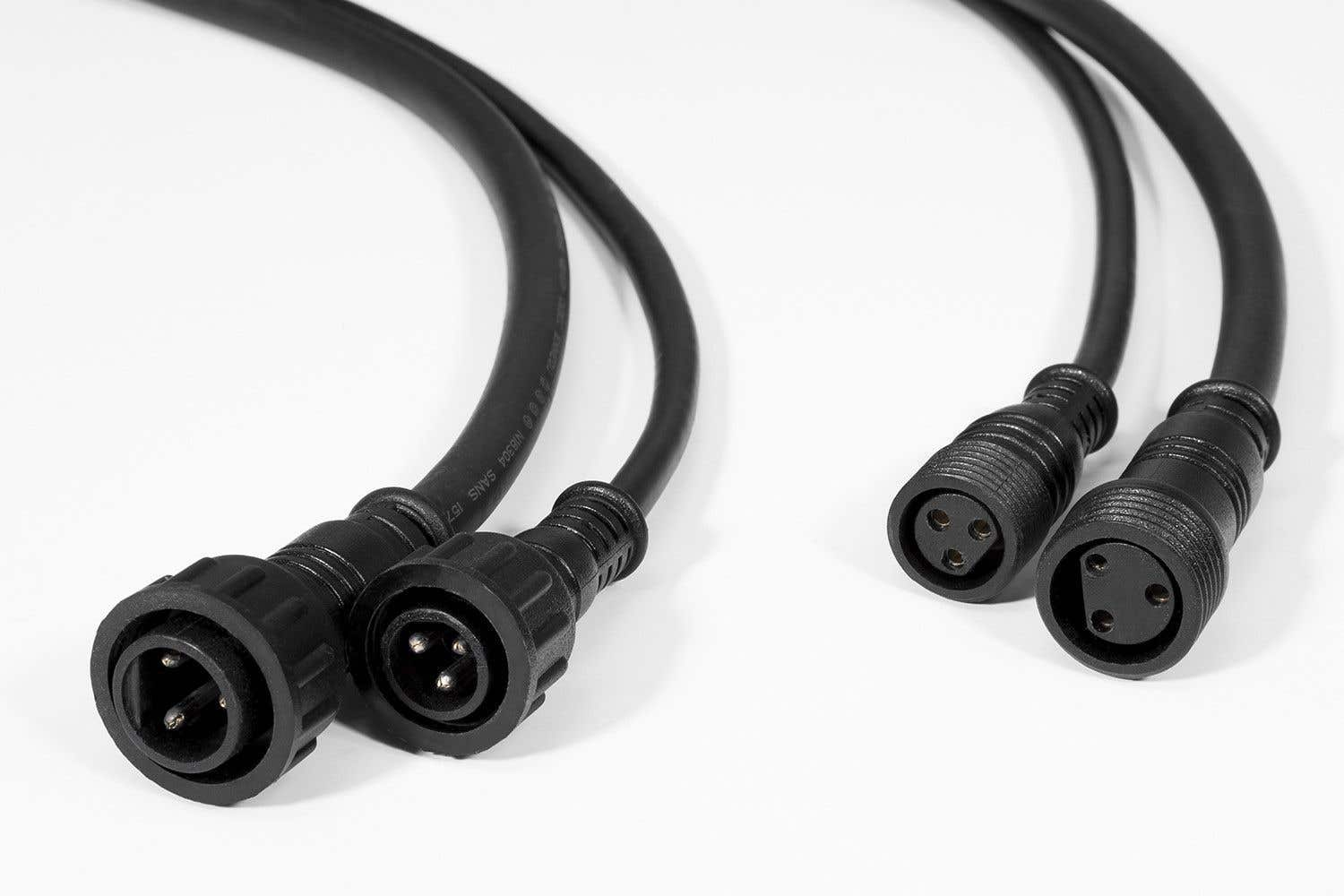 Primer plano de tres cables eléctricos negros con conectores sobre una superficie blanca. Los conectores tienen tres orificios.