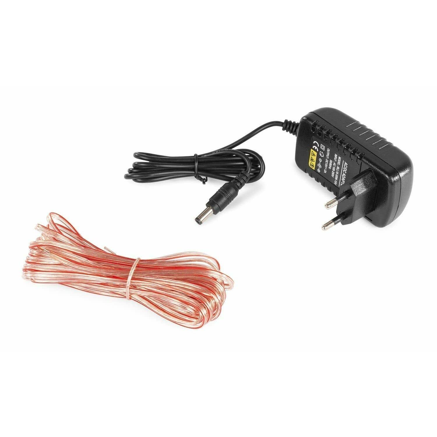 Un adaptador de CA/CC y un haz de cables de cobre están sobre una superficie blanca. El adaptador es negro. Los cables son rojos y cobrizos.