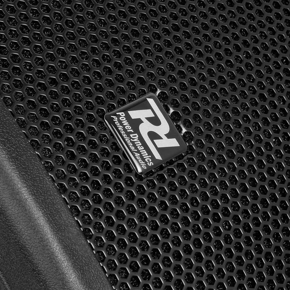 Close-up van een zwart luidsprekerrooster met een honingraatpatroon. Een wit en zilver Power Dynamics logo staat erop.