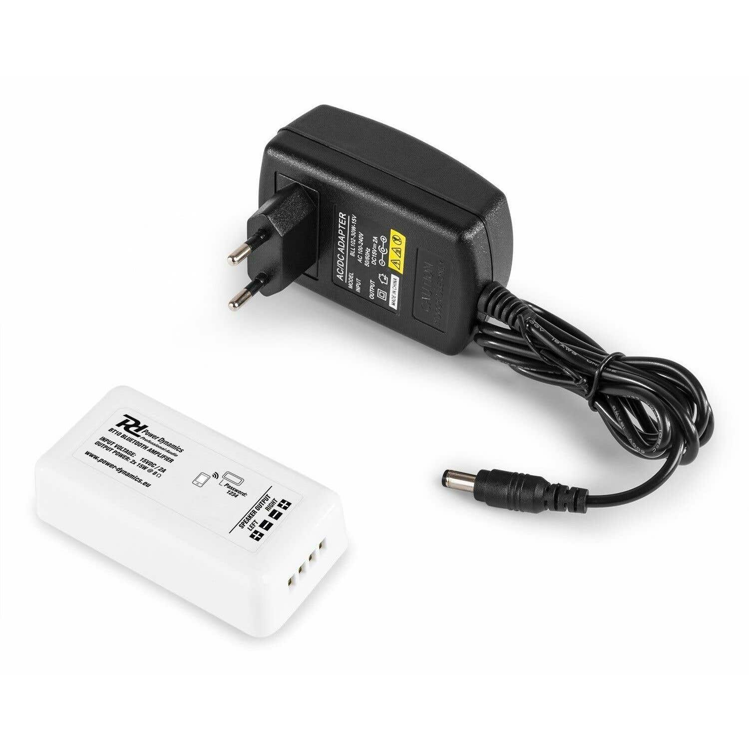 Adaptador AC/DC negro con un amplificador blanco. El amplificador tiene salidas de altavoz y una contraseña. El adaptador tiene un enchufe y cable CC.
