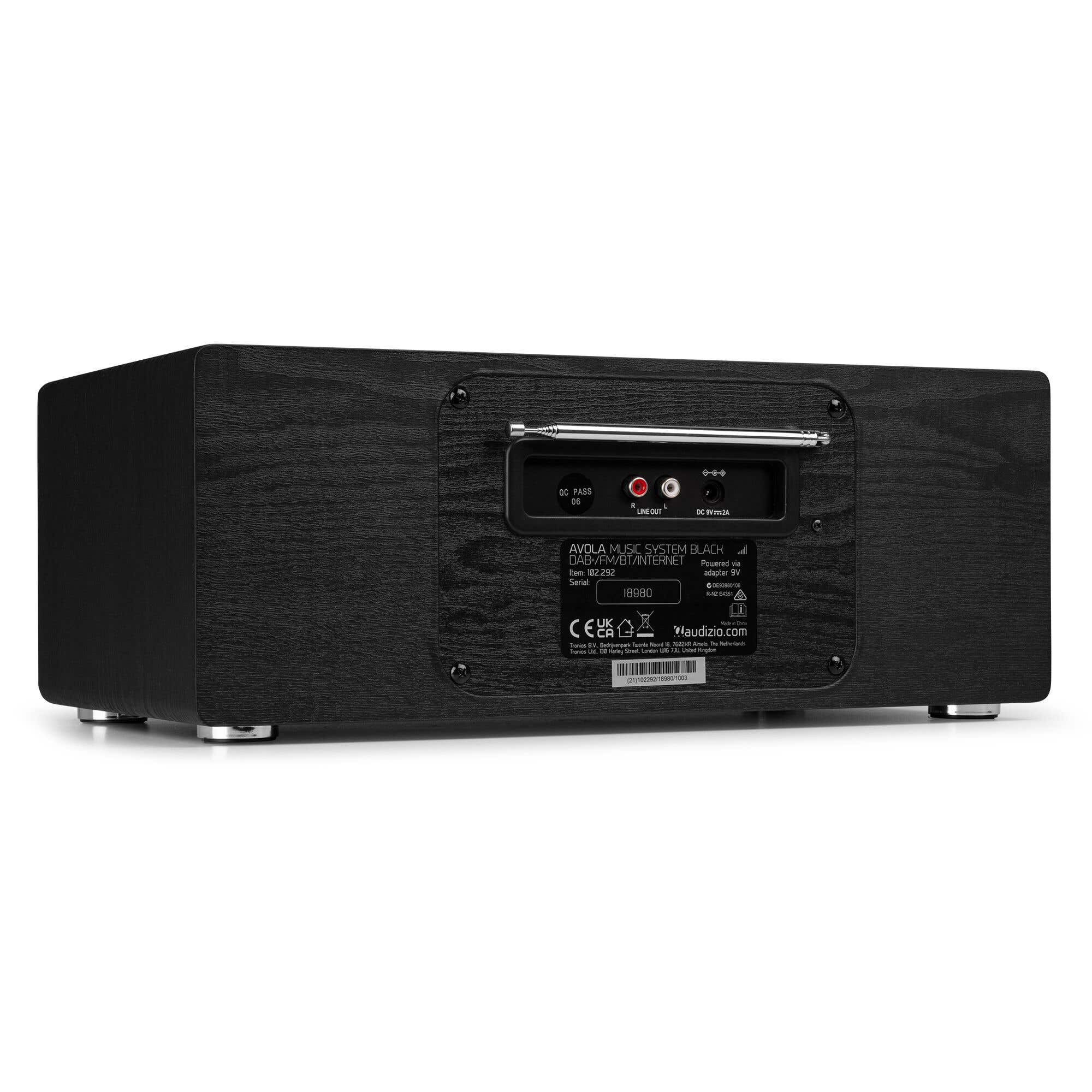 Schwarzes Holzradio mit Anschlüssen und Etiketten. Text lautet AVOLA MUSIC SYSTEM BLACK. Silberne Füße und Antenne sichtbar.