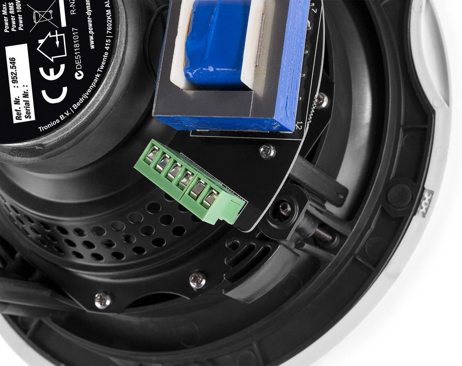 Primer plano de componentes electrónicos. Se ven una regleta verde, un componente azul y blanco y un marco de altavoz negro.