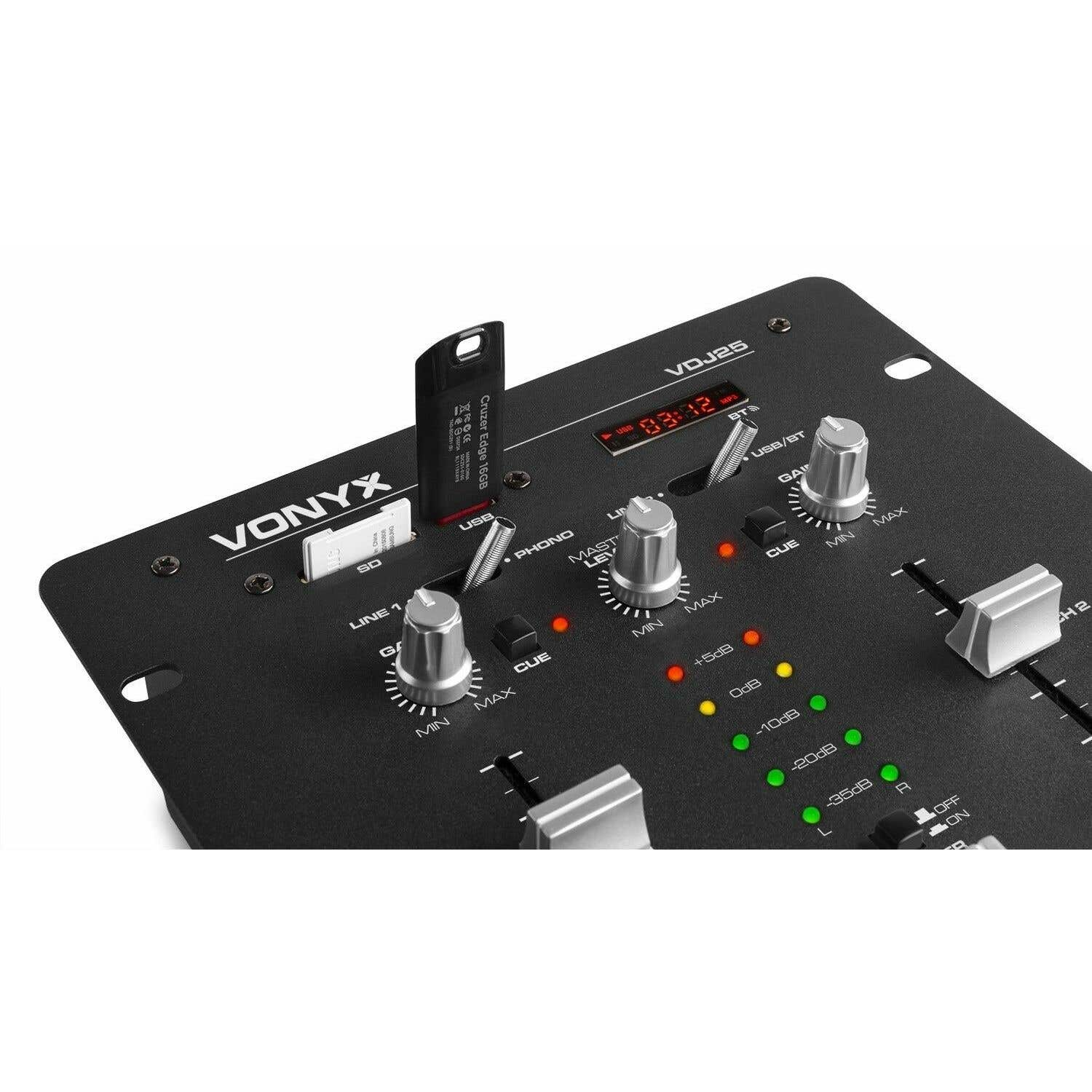 Una mesa de mezclas de DJ negra con una unidad USB insertada. Se ven perillas, deslizadores y luces. La pantalla muestra '03:12'.