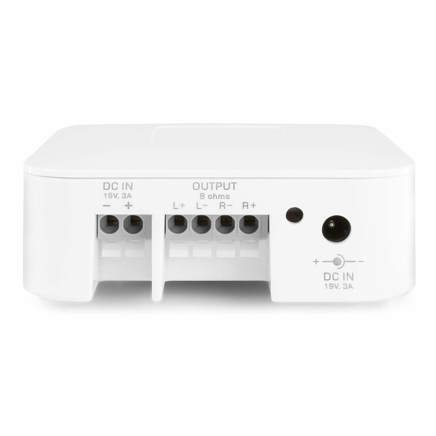 Un dispositivo electrónico blanco con puertos etiquetados DC IN y OUTPUT. El texto incluye voltaje y amperaje, con terminales marcados más, menos y L, R.