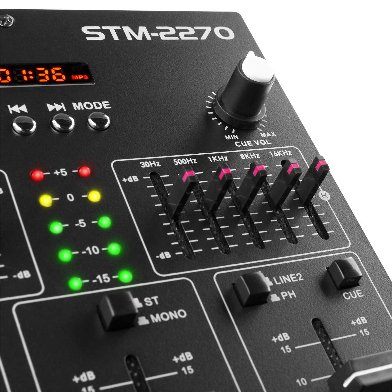 Primer plano de una mesa de mezclas de audio negra. Se ven perillas, deslizadores e indicadores LED. El texto dice STM-2270. La mesa tiene controles de nivel.
