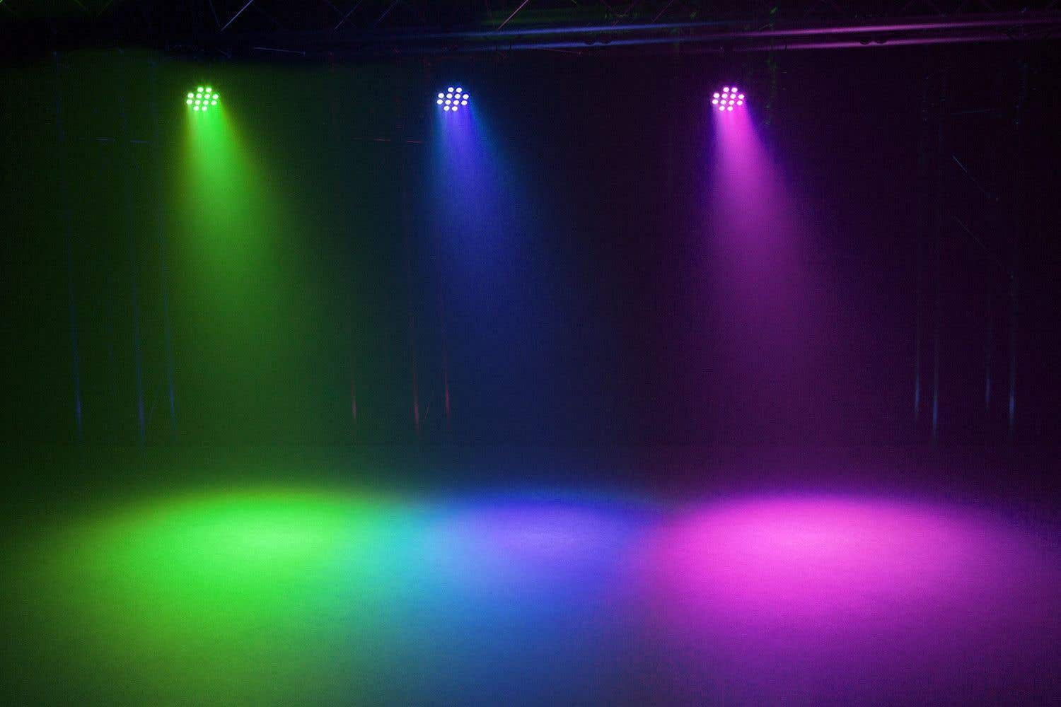 Iluminación de escenario con focos verdes, azules y morados. Los haces brillan hacia abajo, iluminando el suelo.