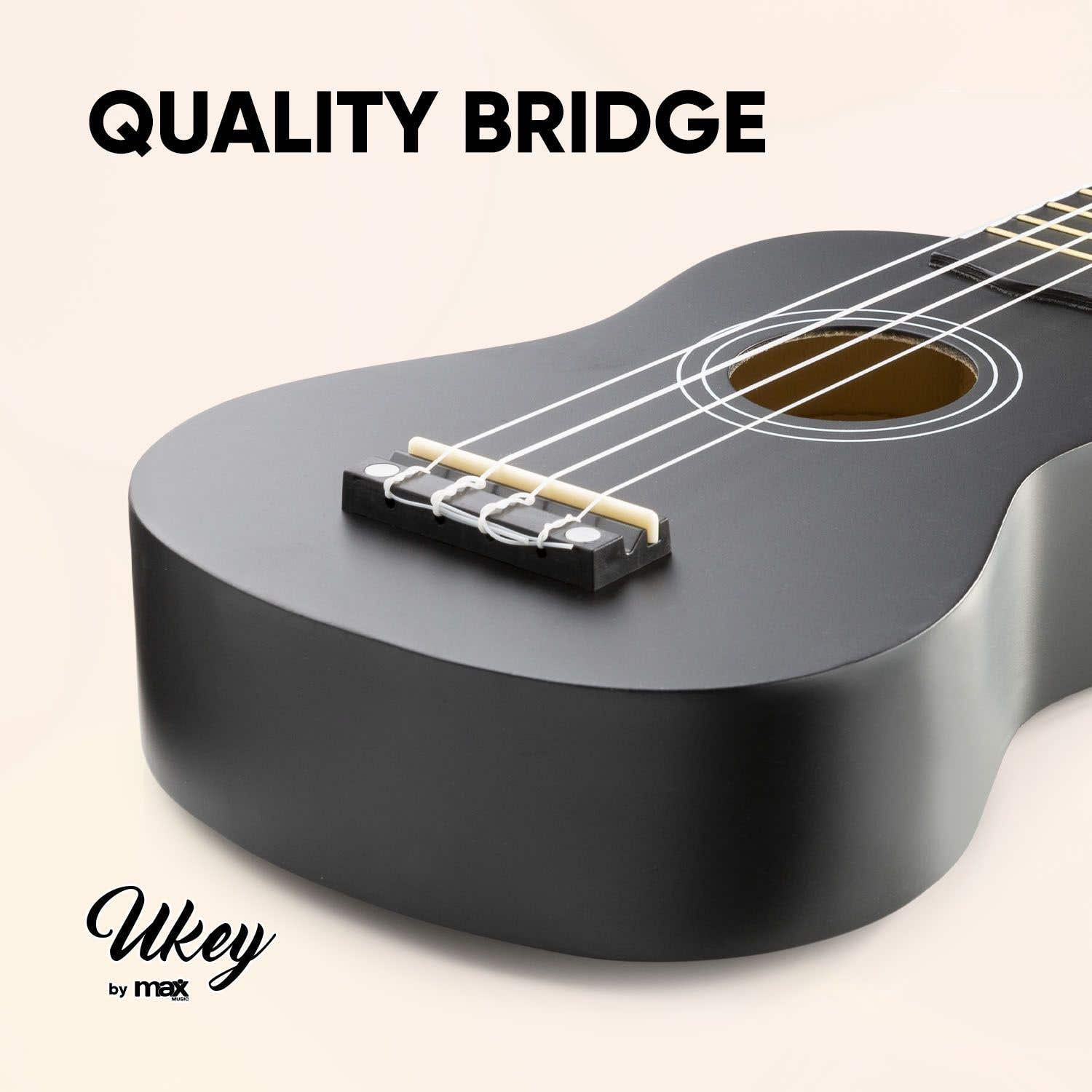 Ukelele negro, con la etiqueta 'Quality Bridge' y 'Ukey by max'. Cuerdas y boca visibles. Fondo crema.
