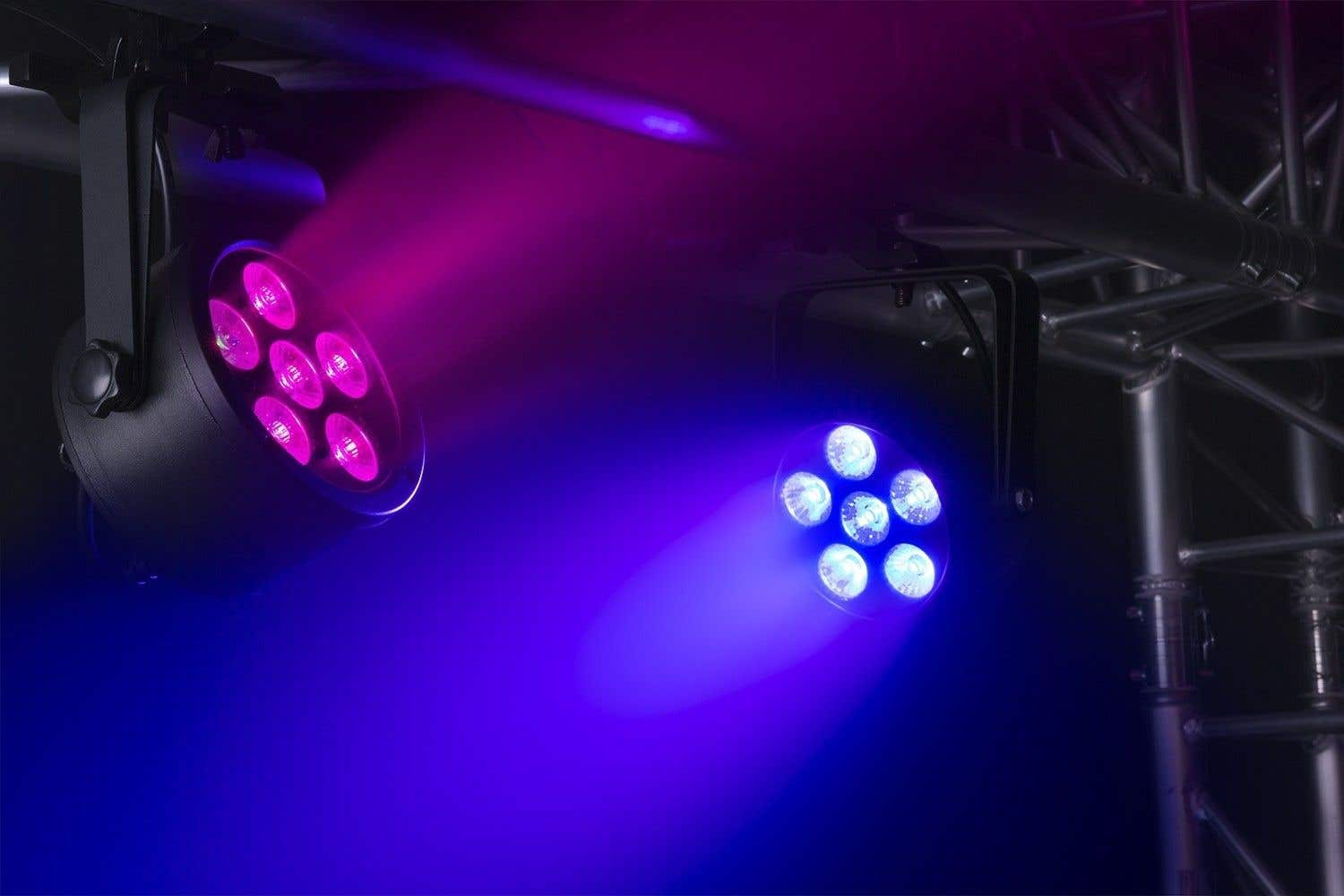 Dos luces de escenario emiten haces rosas y azules. Una tiene luces rosas, la otra luces azules.