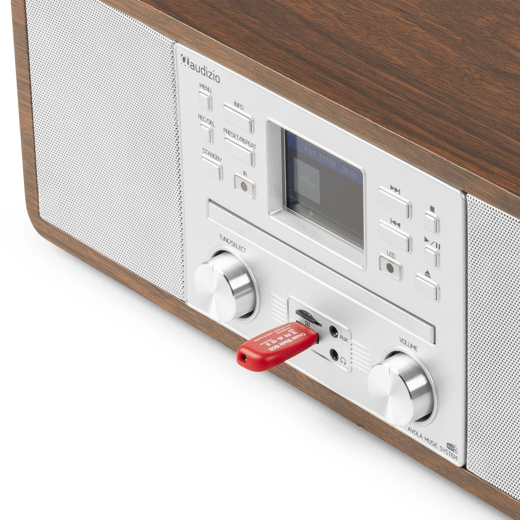 Une radio en bois et argent avec une clé USB insérée. L'écran affiche les informations de la station de radio. Des boutons et des boutons sont visibles.