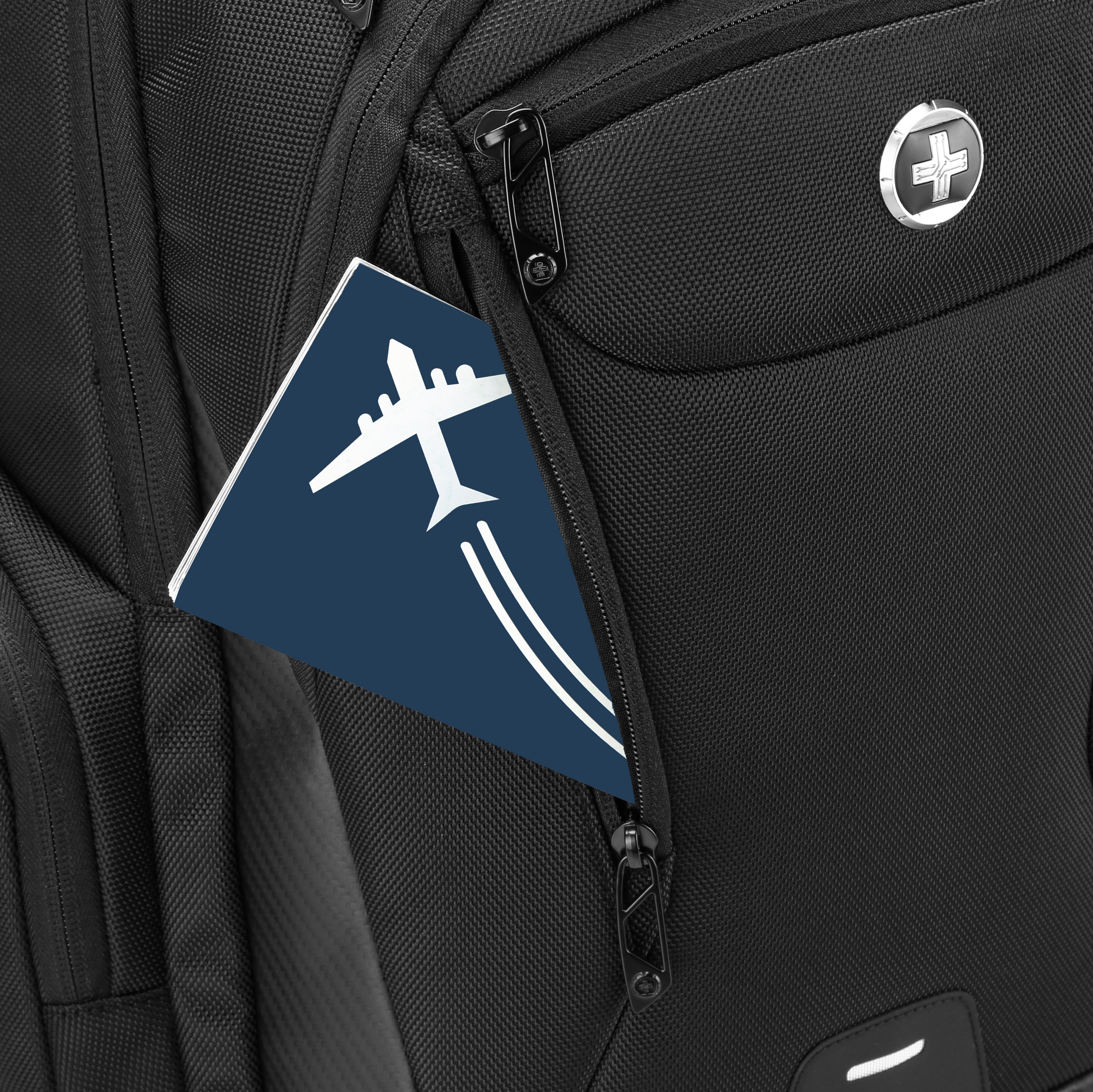 Zaino nero con passaporto raffigurante un aereo. Logo a croce argentata sul lato. Cerniera parzialmente aperta.