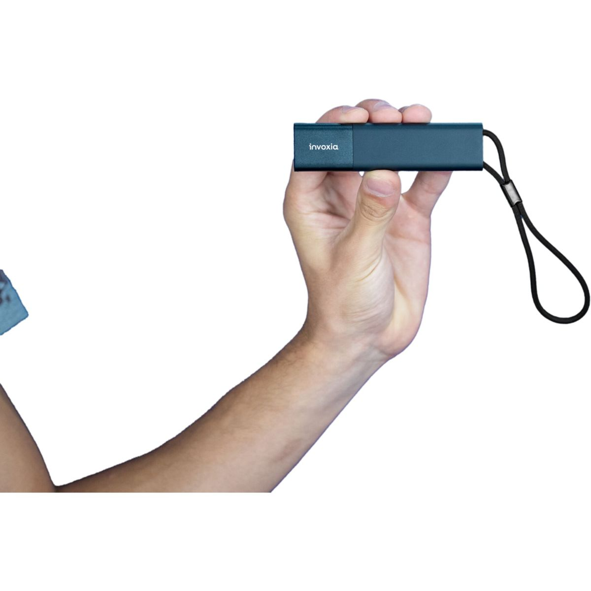 Ręka trzyma turkusowy tracker Invoxia. Dołączona jest czarna smycz. Tło jest białe.