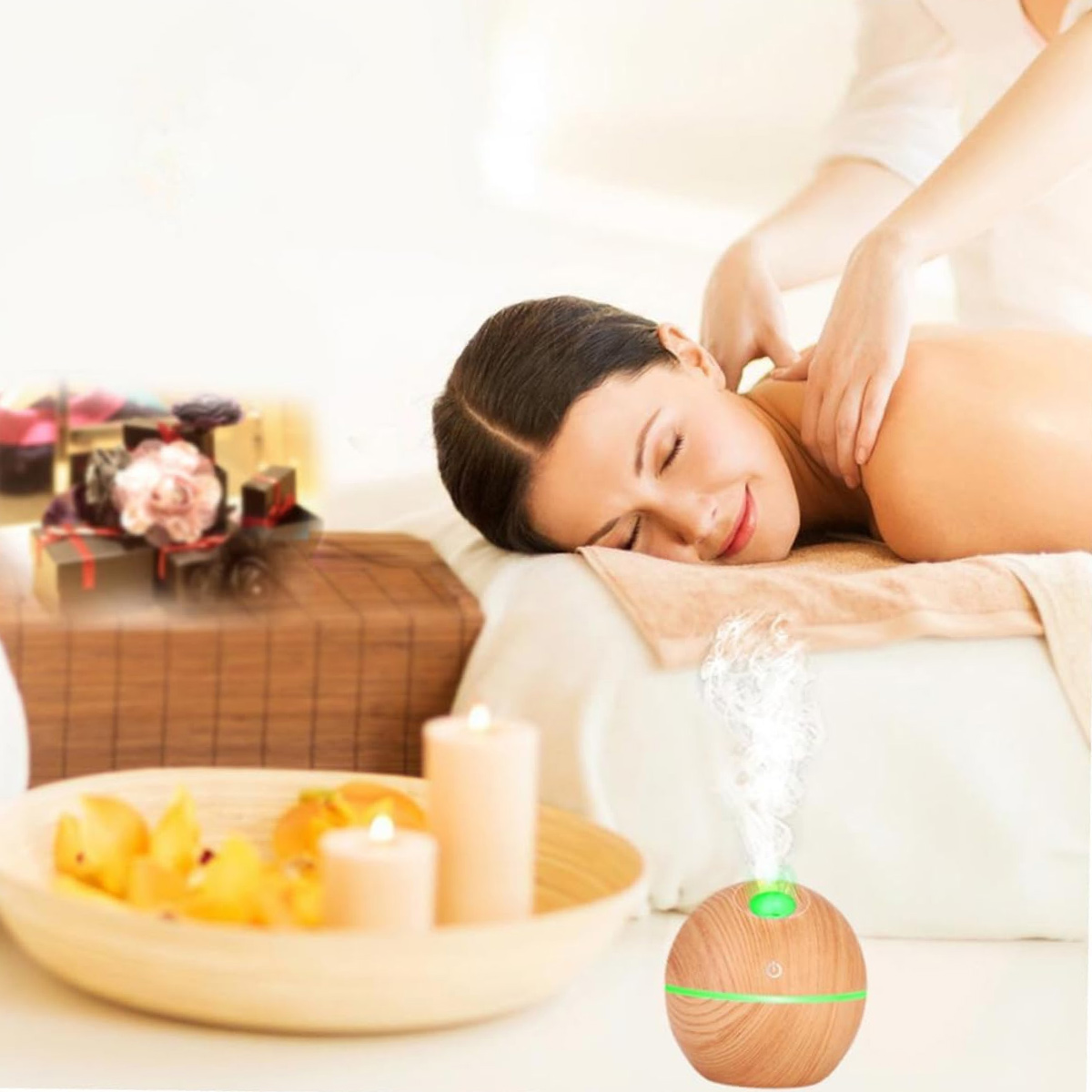 Eine Frau erhält eine Massage im Spa. Kerzen, Geschenke und ein Diffusor mit Dampf sind sichtbar, was eine entspannende Atmosphäre schafft.