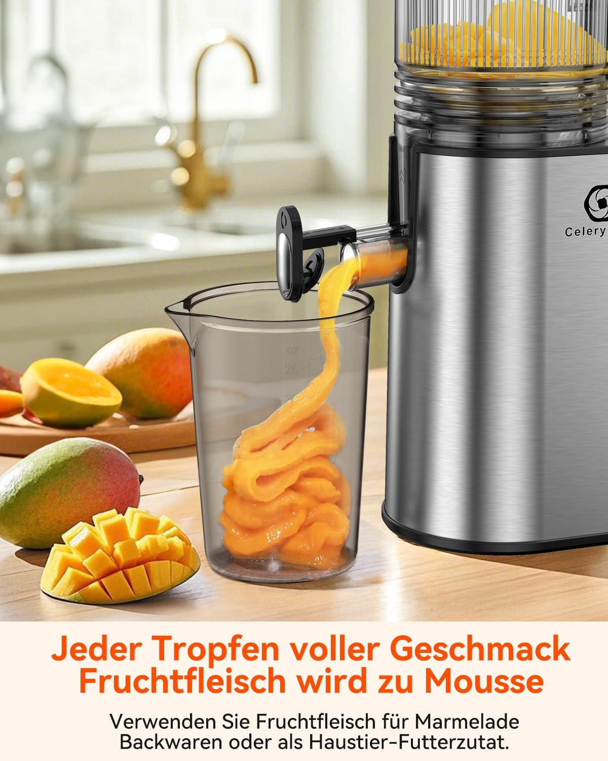 Ein Entsafter presst Saft in ein Glas. Mangos liegen auf dem Tisch. Die Maschine und der Saft sind silber und orange.