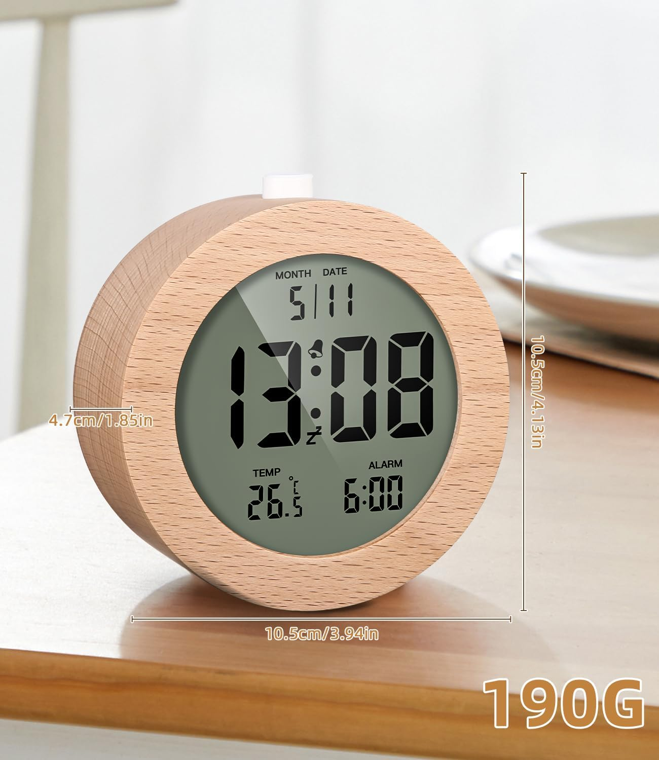 Una sveglia in legno mostra l'ora 13:08, la data 5/11 e la temperatura 26,5°C. È su un tavolo di legno.